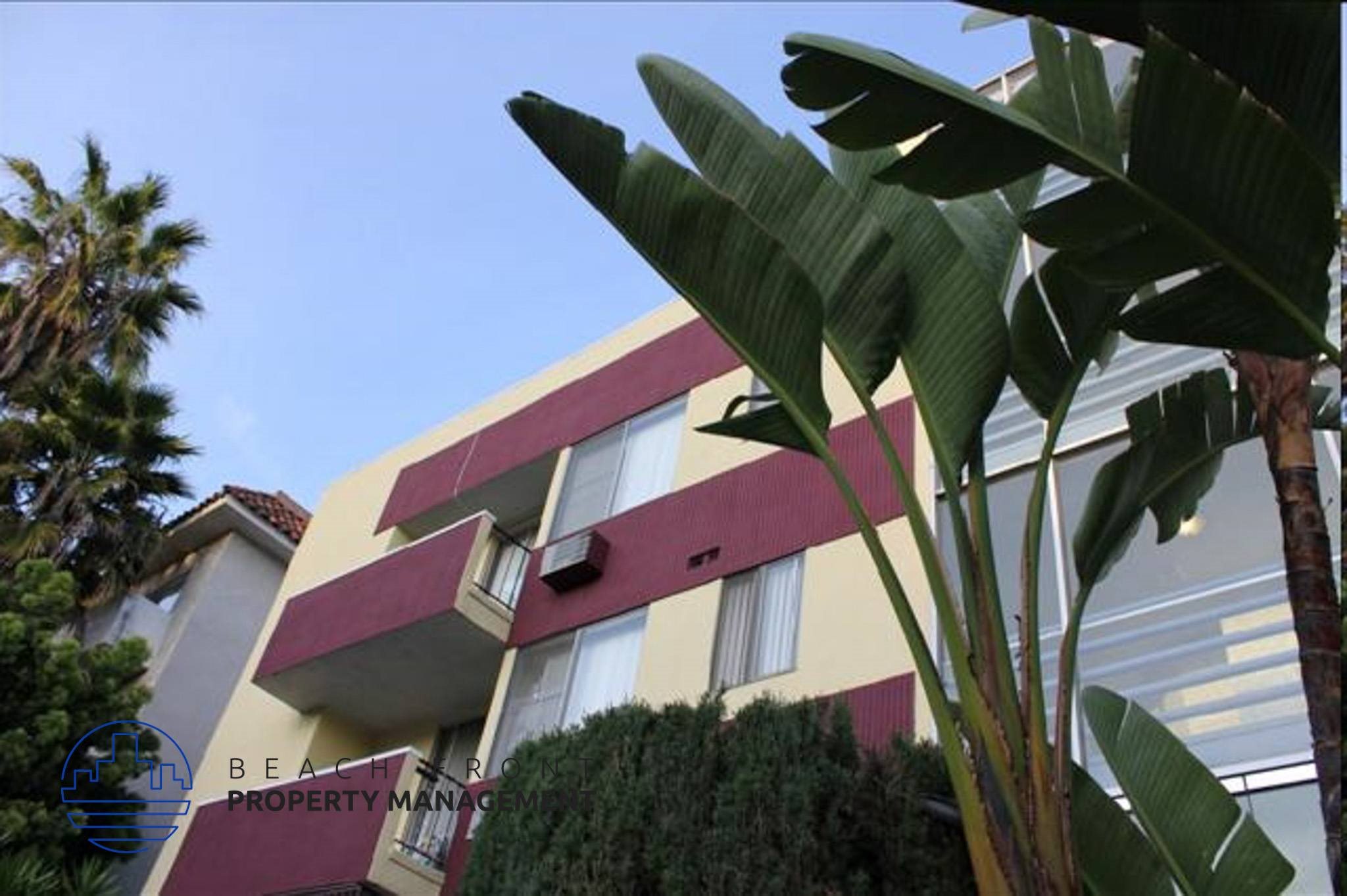 A building with a red and yellow facade is surrounded by greenery.