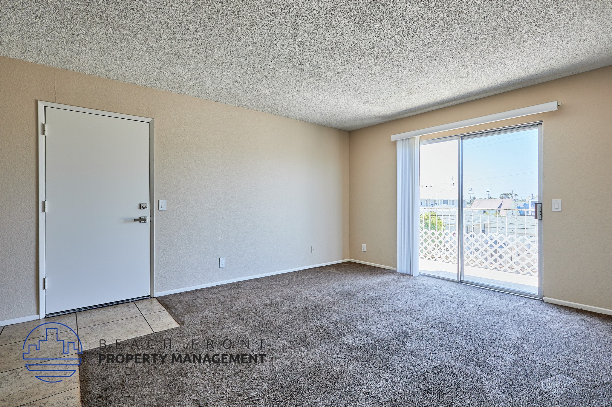 A room with a carpeted floor, a sliding glass door, and a white door.