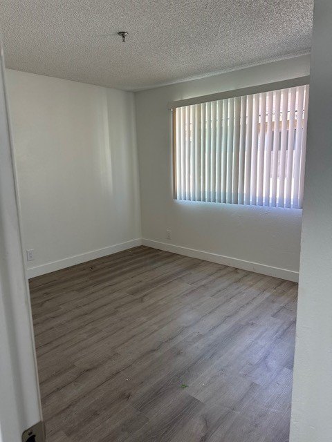 A room with a window covered by blinds and wooden flooring.