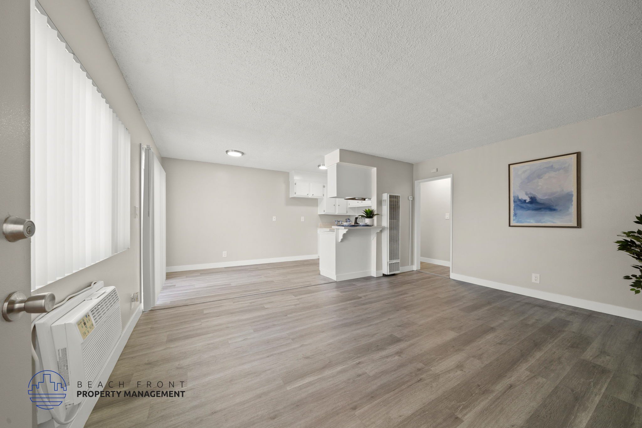 A spacious room with wooden flooring and a white cabinet.