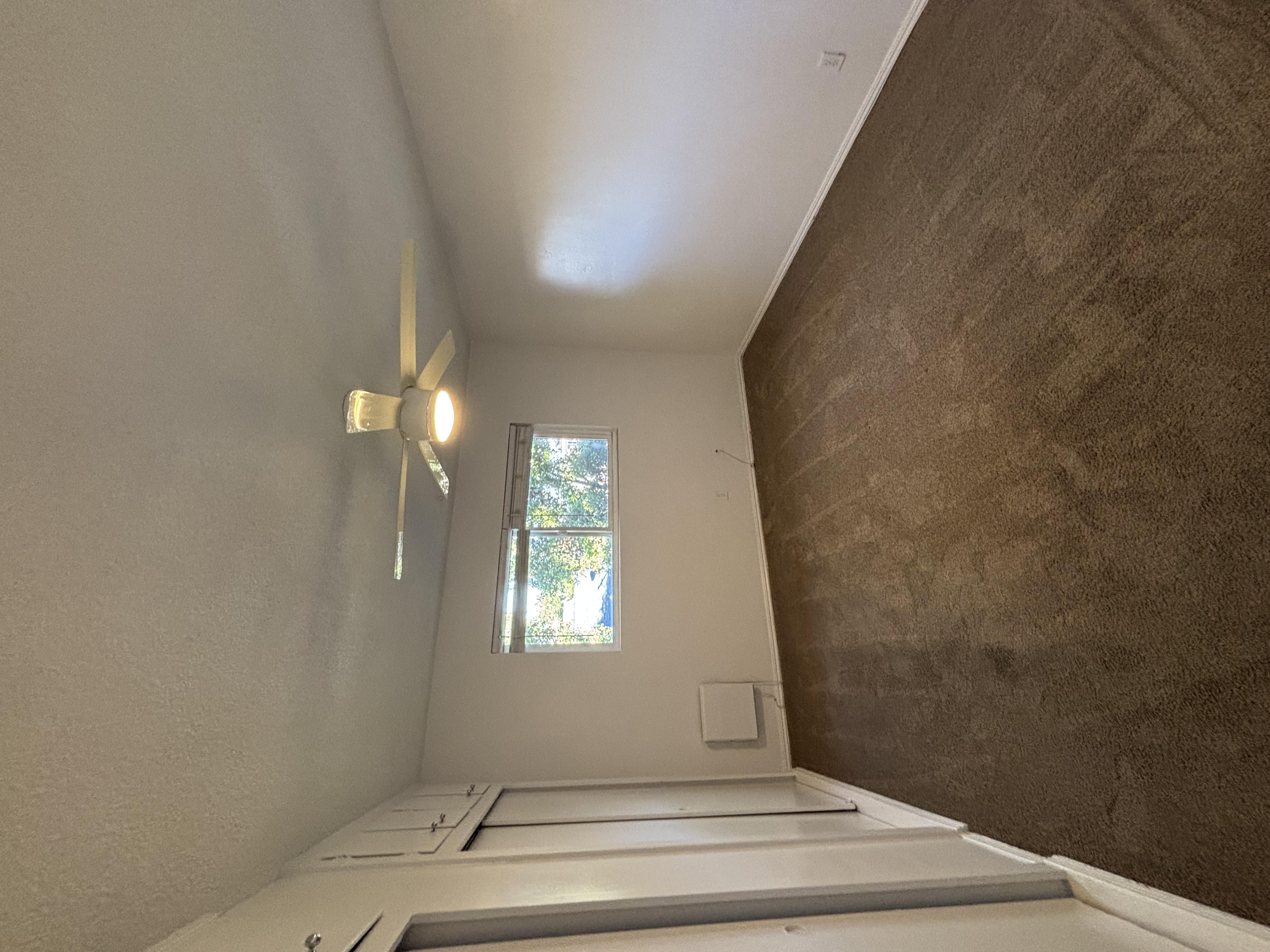 A room with a ceiling fan and a window.