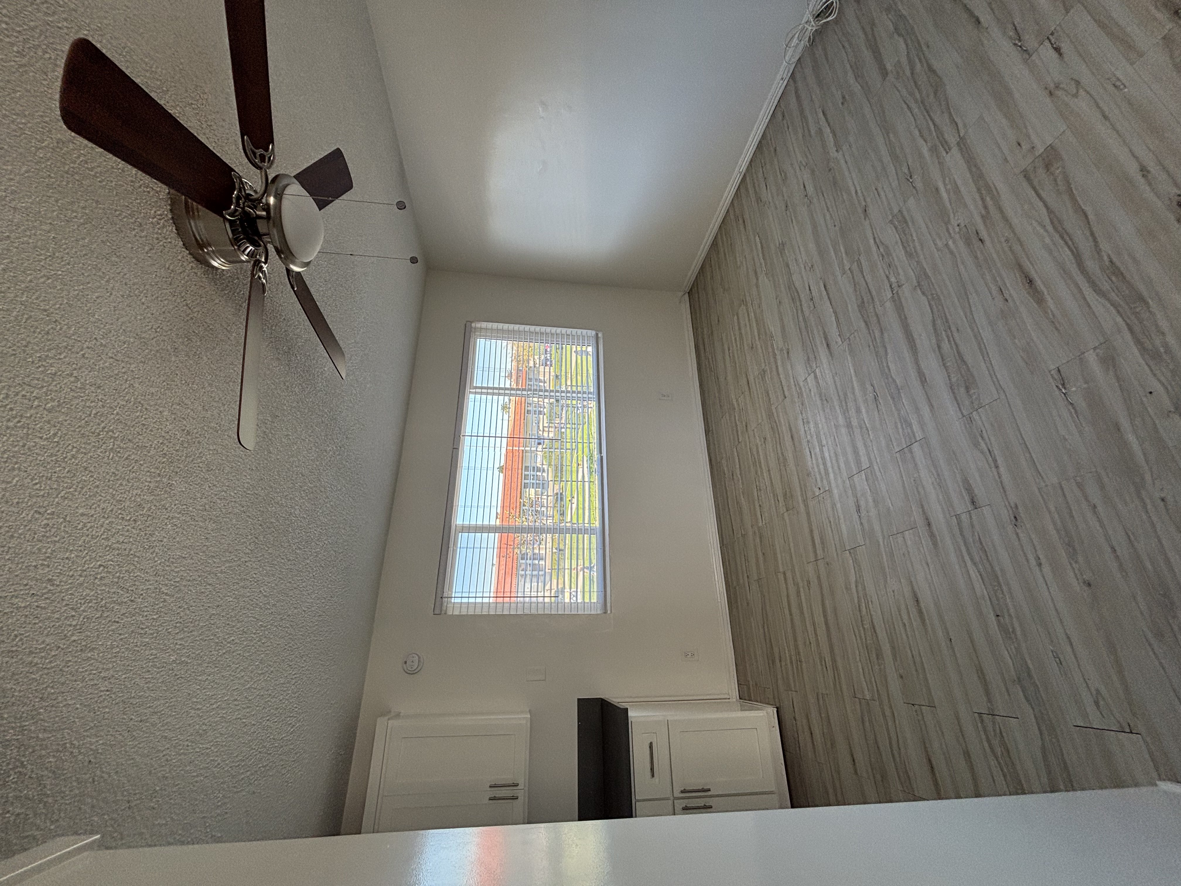 A ceiling fan hangs over a white table in a room with a window.
