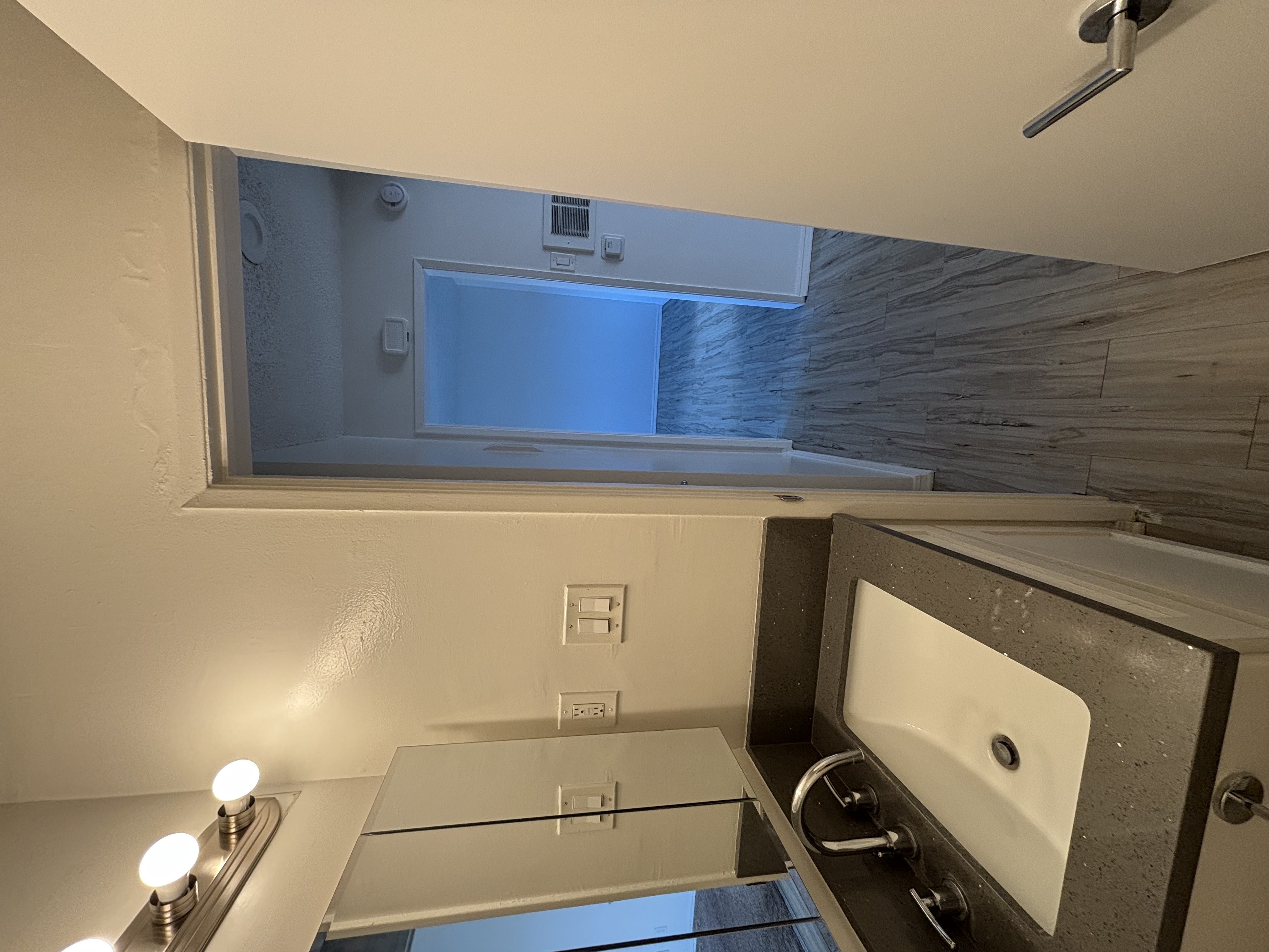 A bathroom with a sink, mirror, and a window.