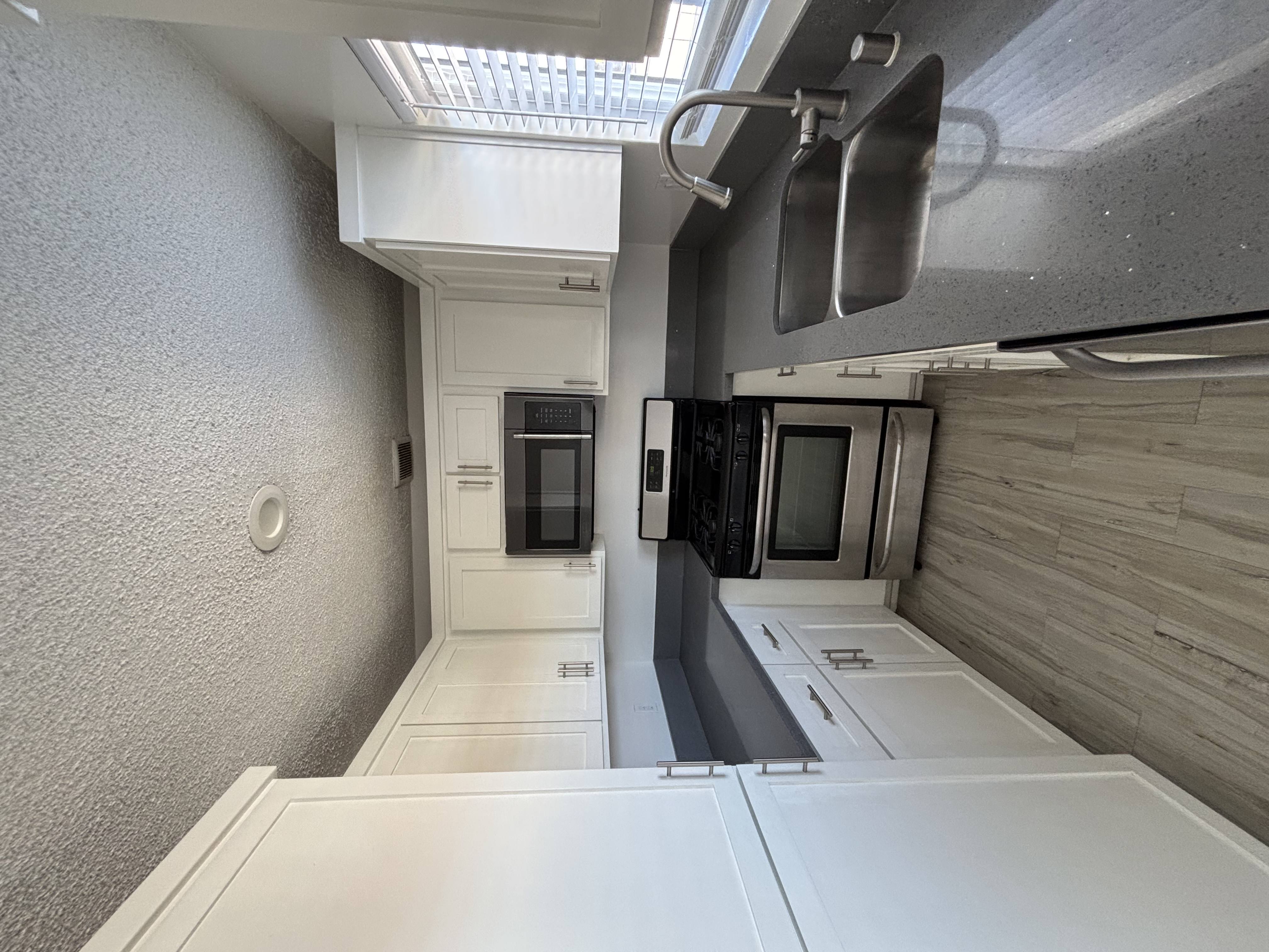 A kitchen with white cabinets and a microwave.