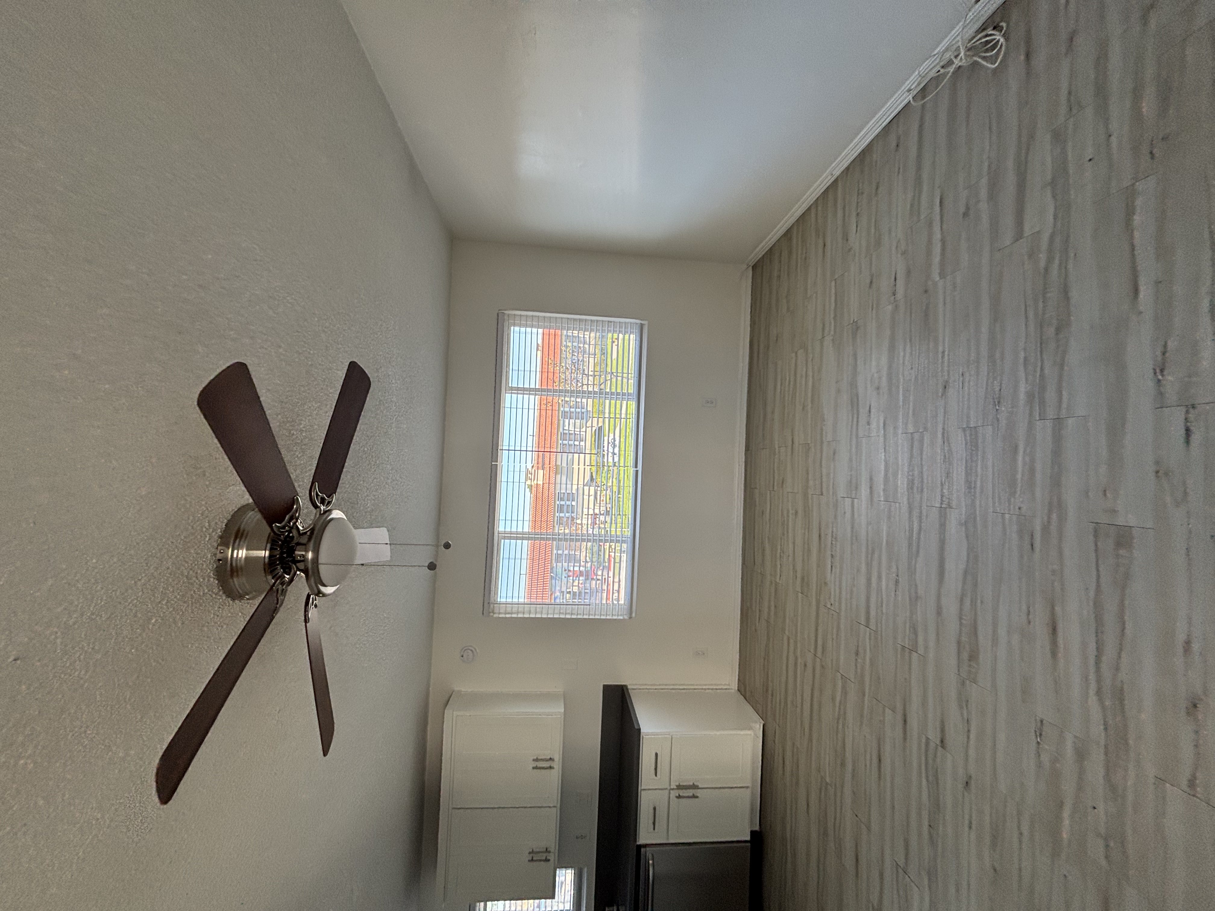 A room with a ceiling fan and a window.
