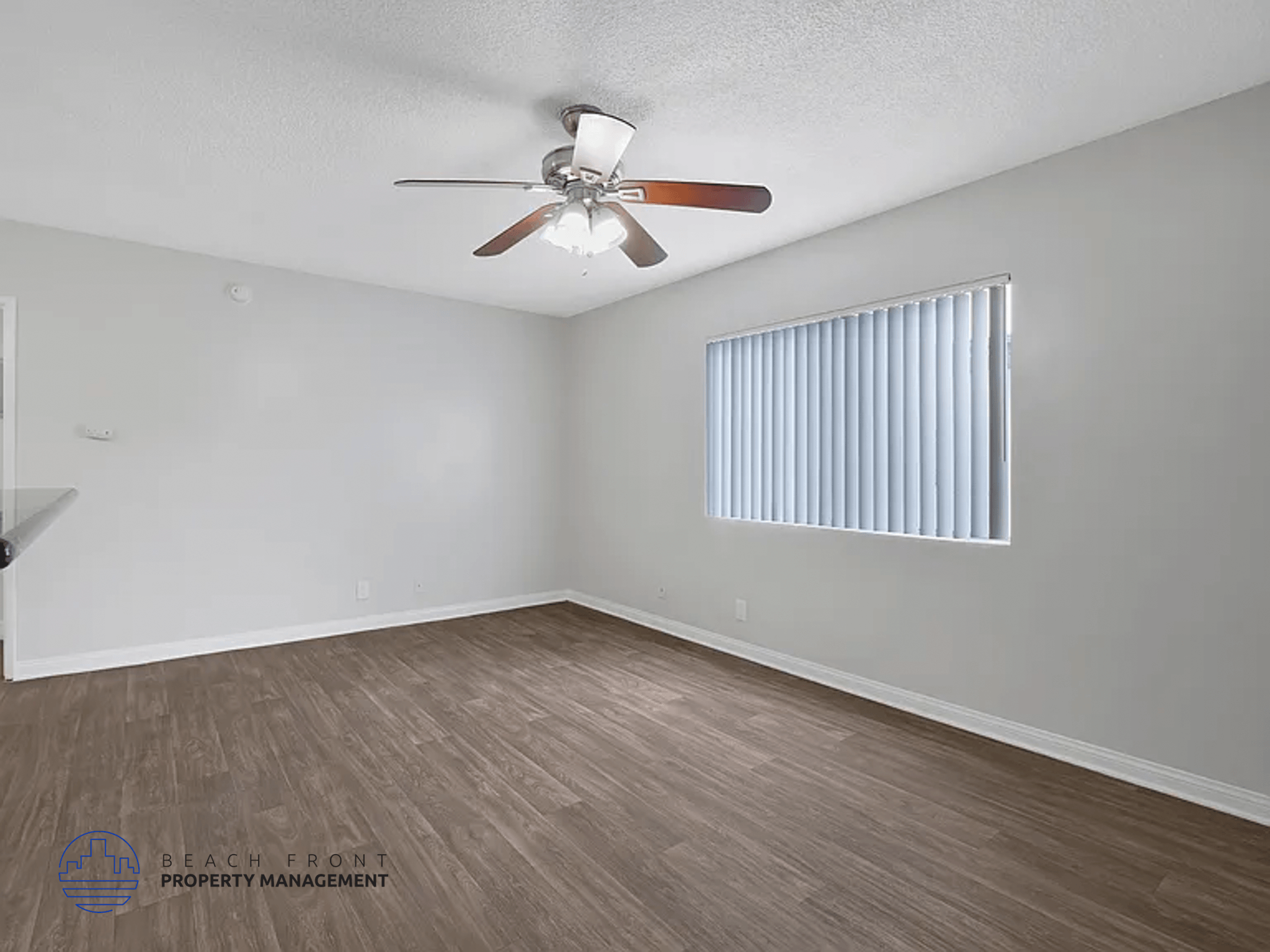 A room with a ceiling fan and a window with blinds.