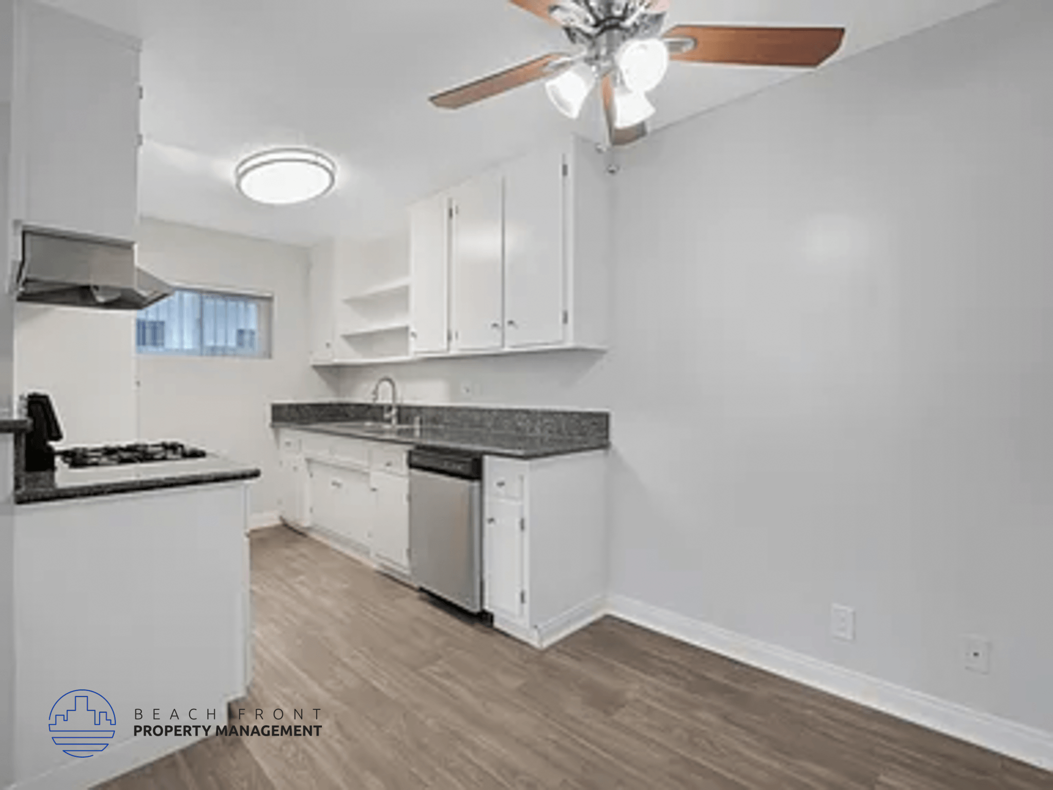 A kitchen with white cabinets and a black countertop.