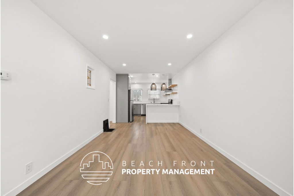 a renovated living room and kitchen with white walls and wood flooring