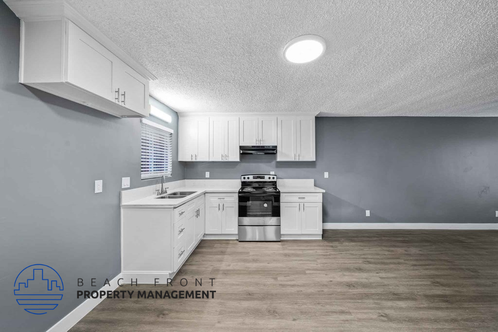 A kitchen with white cabinets and a stove top oven.