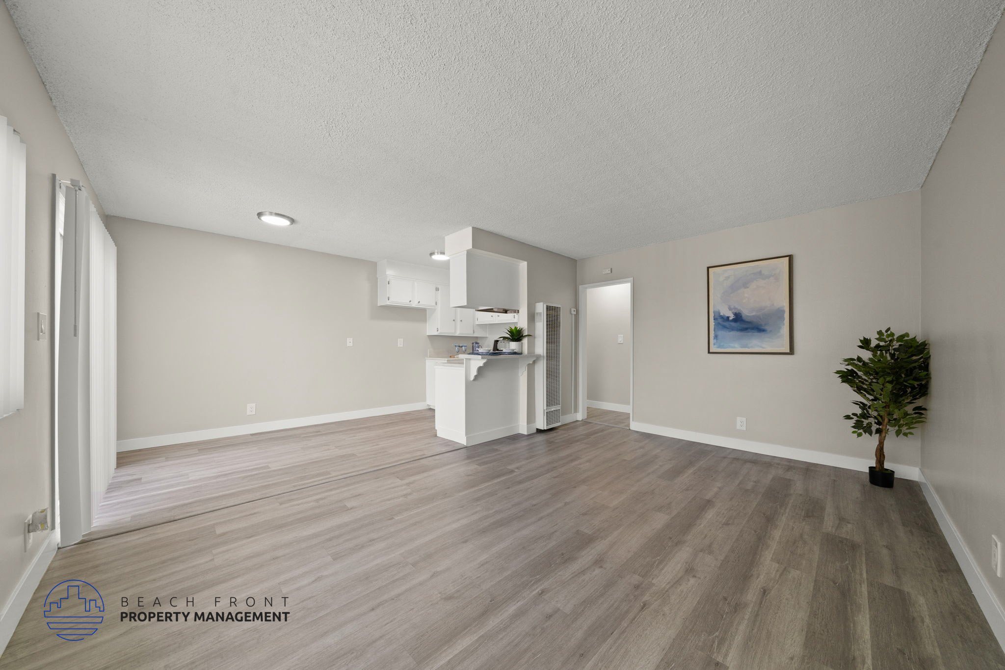 A spacious room with wooden flooring and a white cabinet.