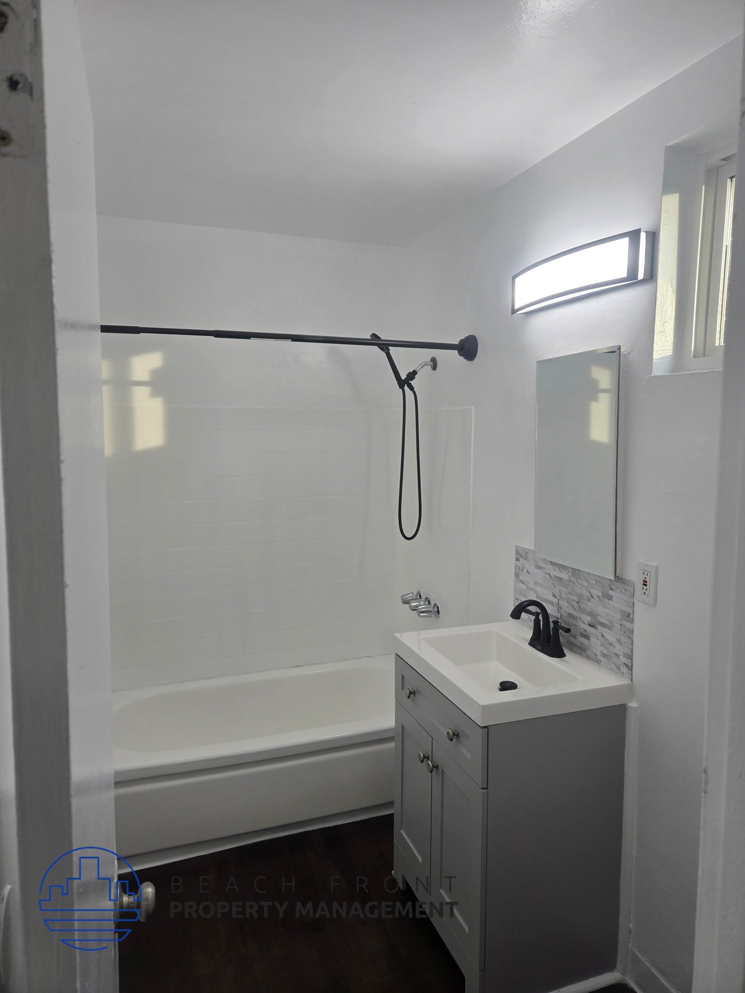 A white bathroom with a sink, mirror, and shower.