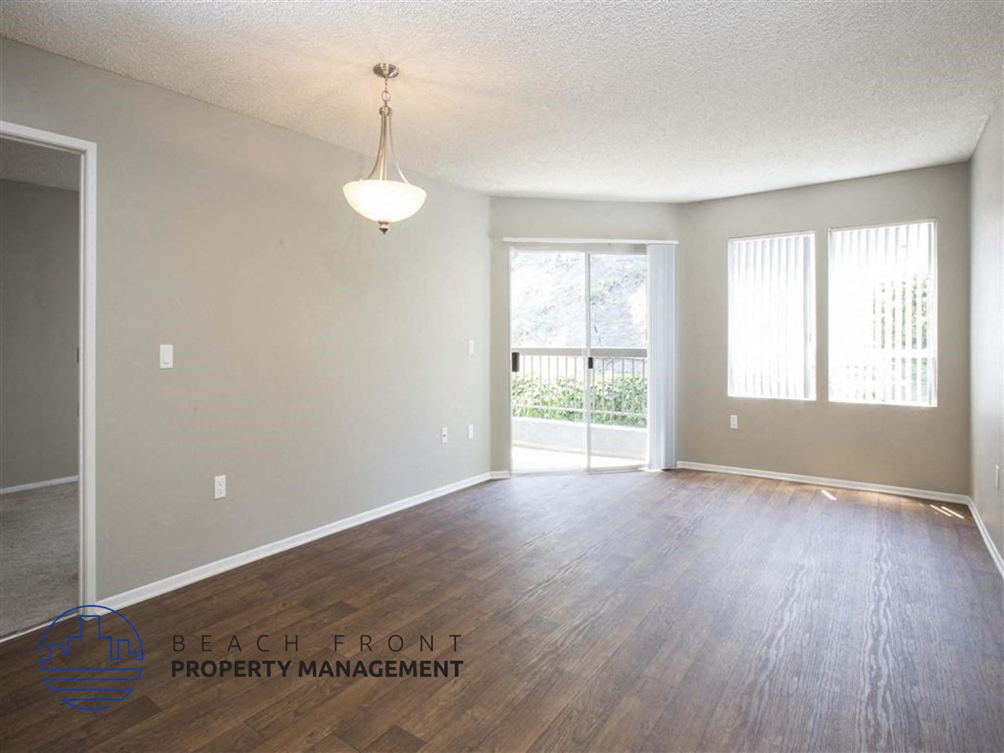 A room with wooden floors and a sliding glass door leading to a balcony.