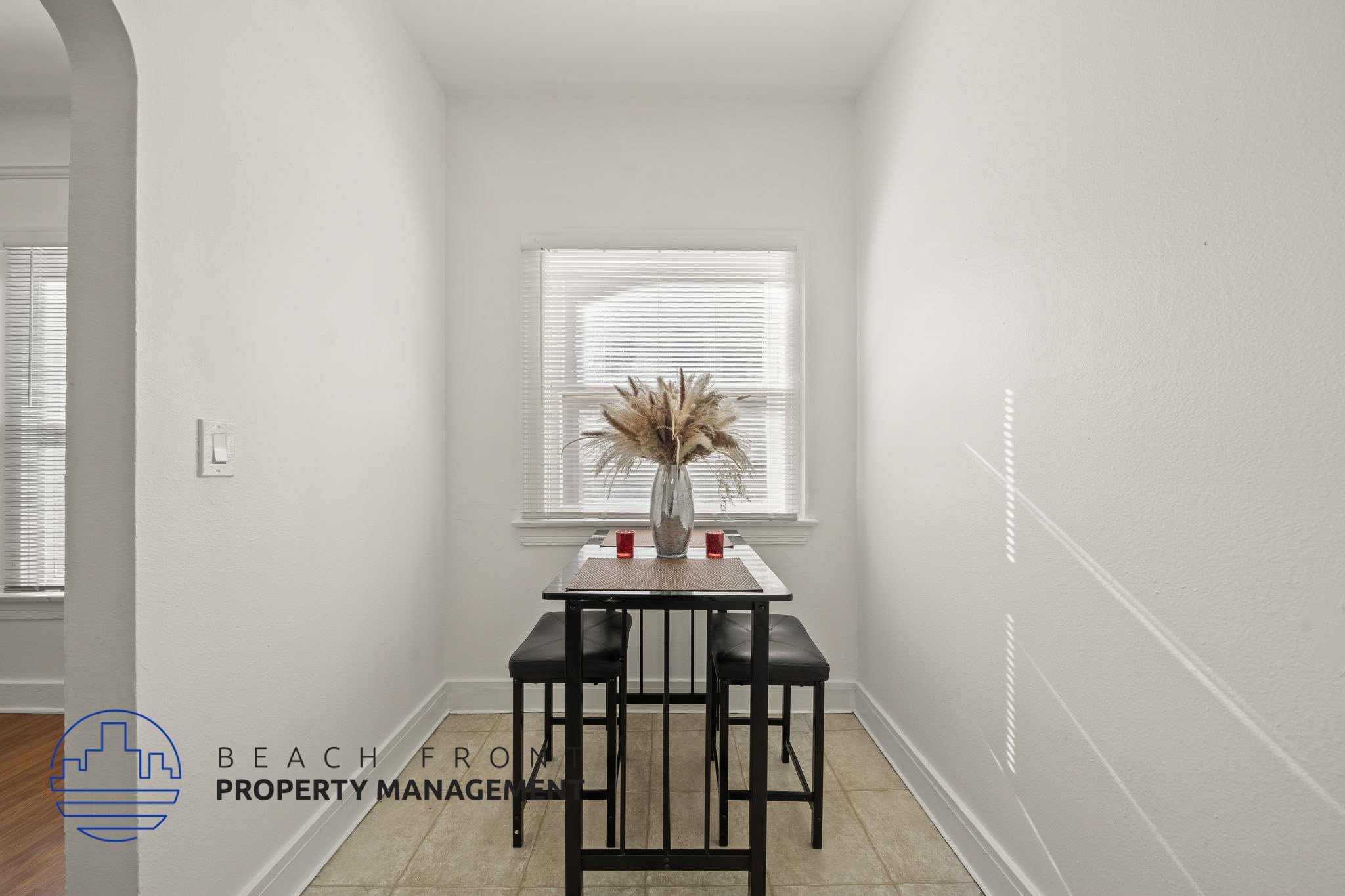 A dining table with two chairs is in a white room with a window.