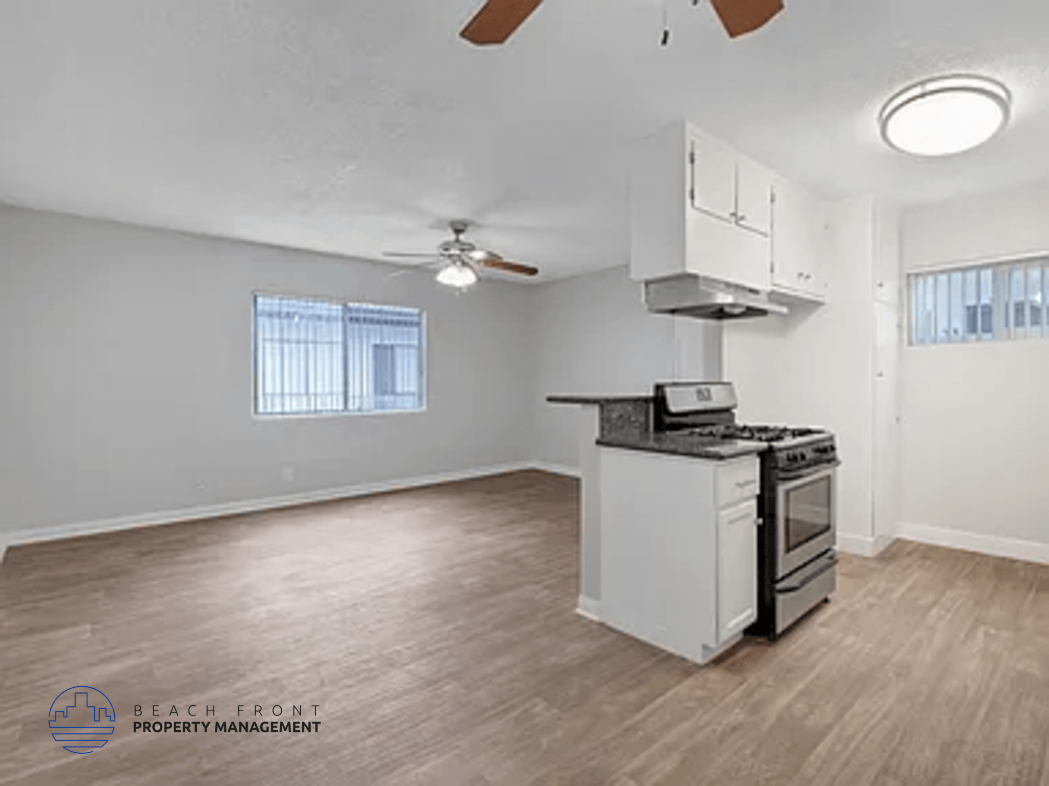 A kitchen with a stove top oven and a fan on the ceiling.