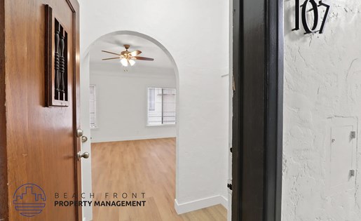 A hallway with a door numbered 107 and a logo for Beachfront Property Management.