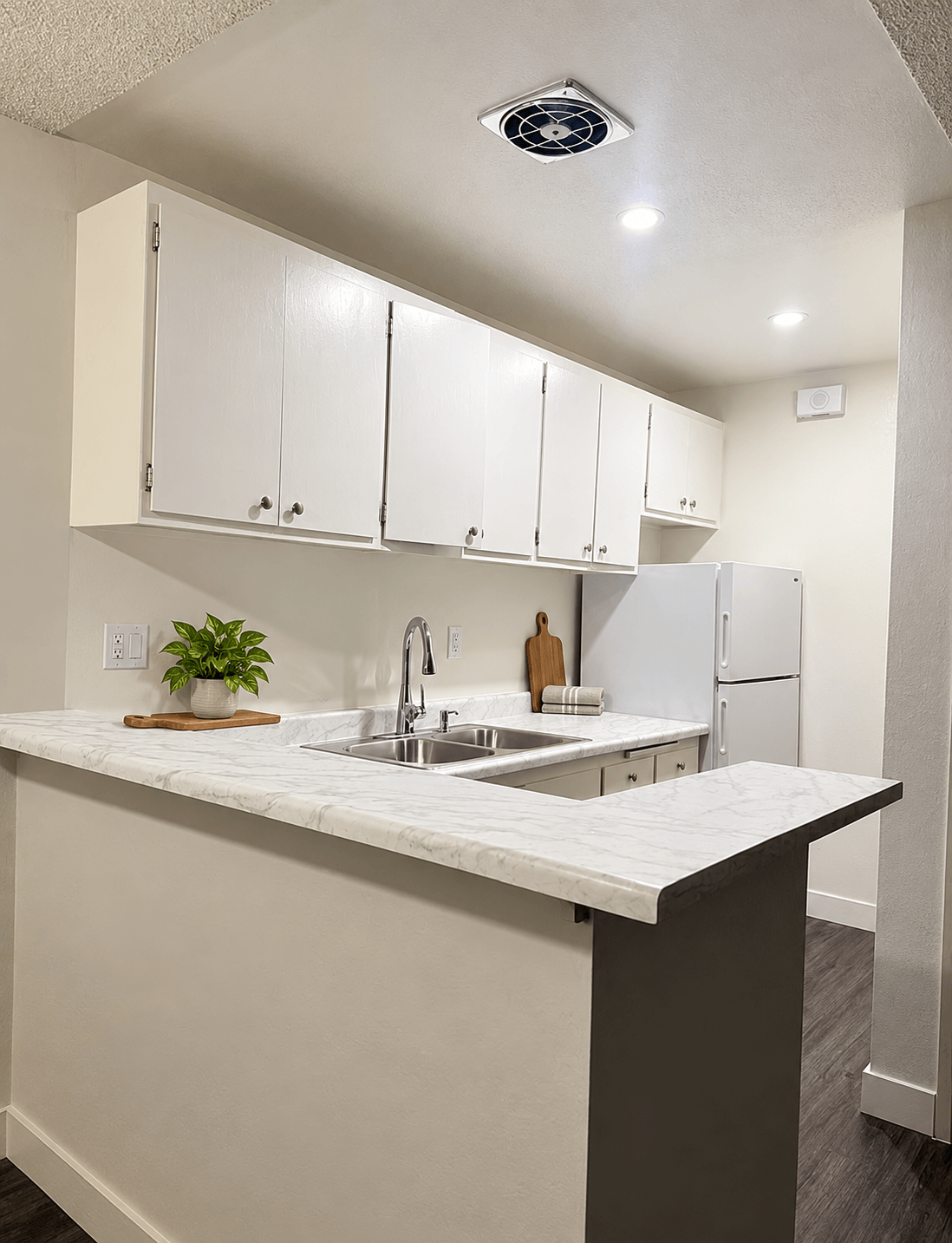 A kitchen with white cabinets and a marble countertop.