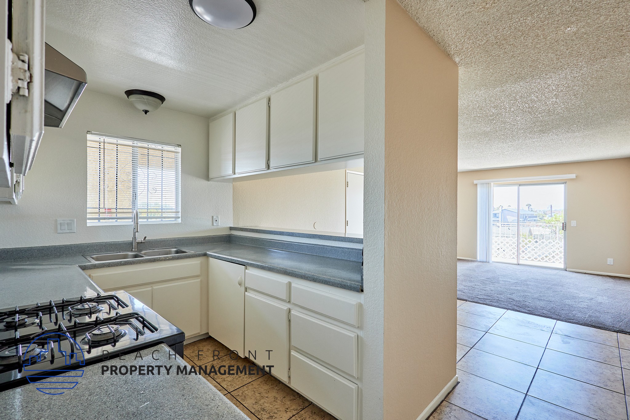A kitchen with a stove, sink, and cabinets.