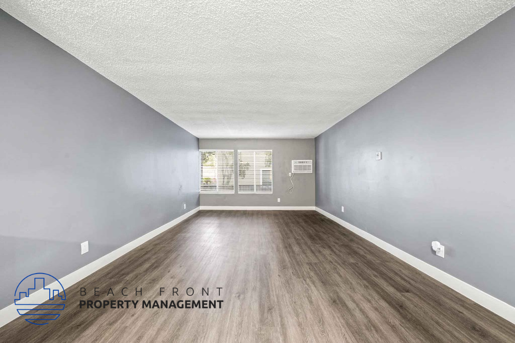 A room with wooden flooring and a logo for Beach Front Property Management.