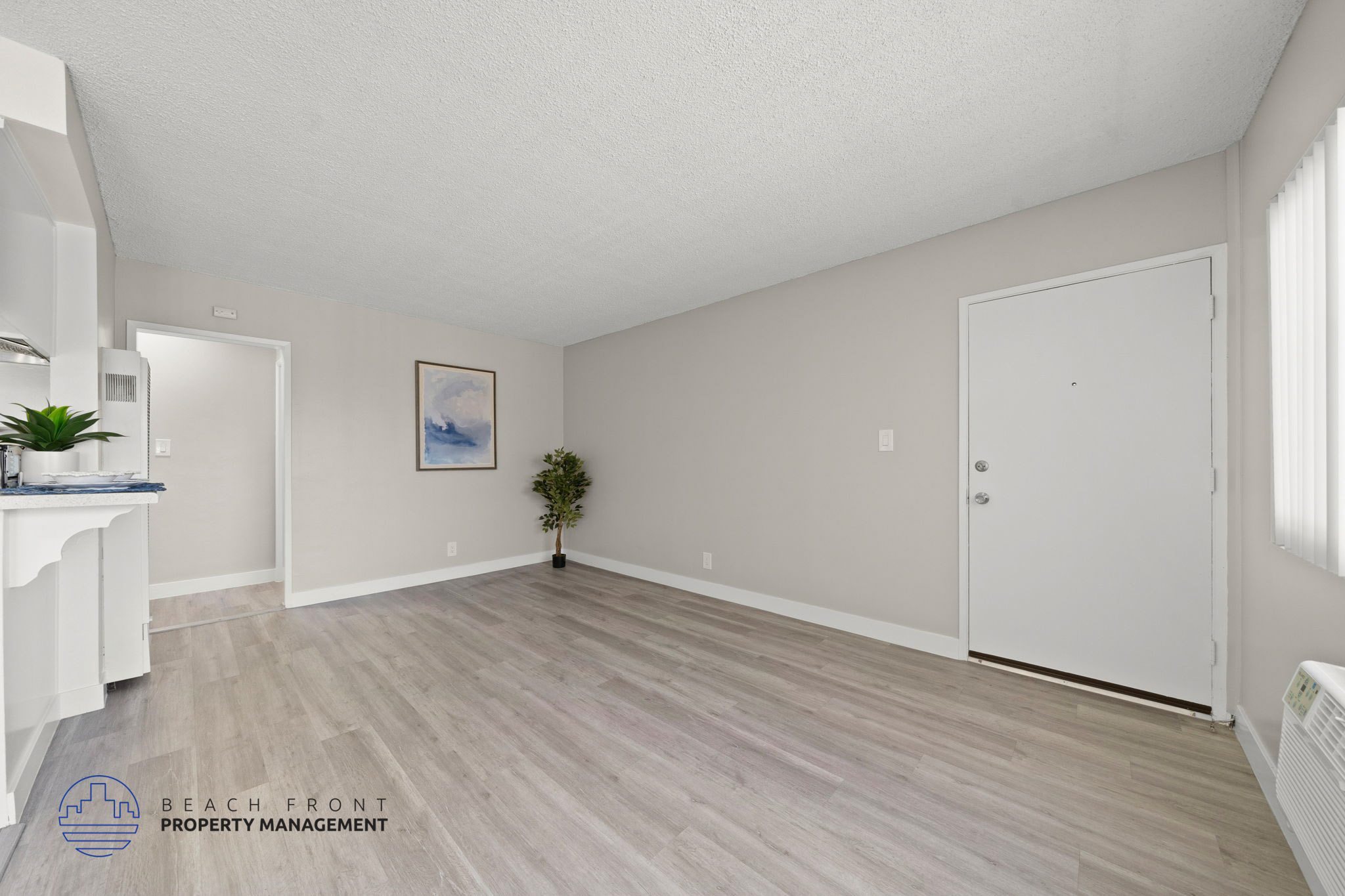 A spacious room with light wood flooring and a white door.