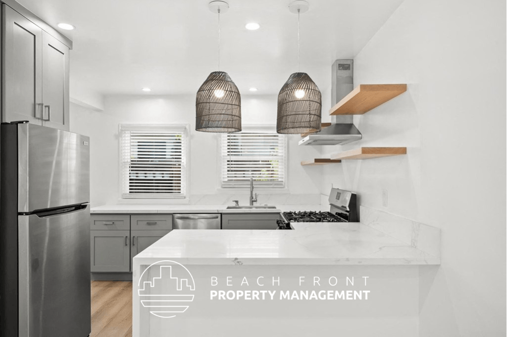 a white and gray kitchen with two pendant lights and a white counter top