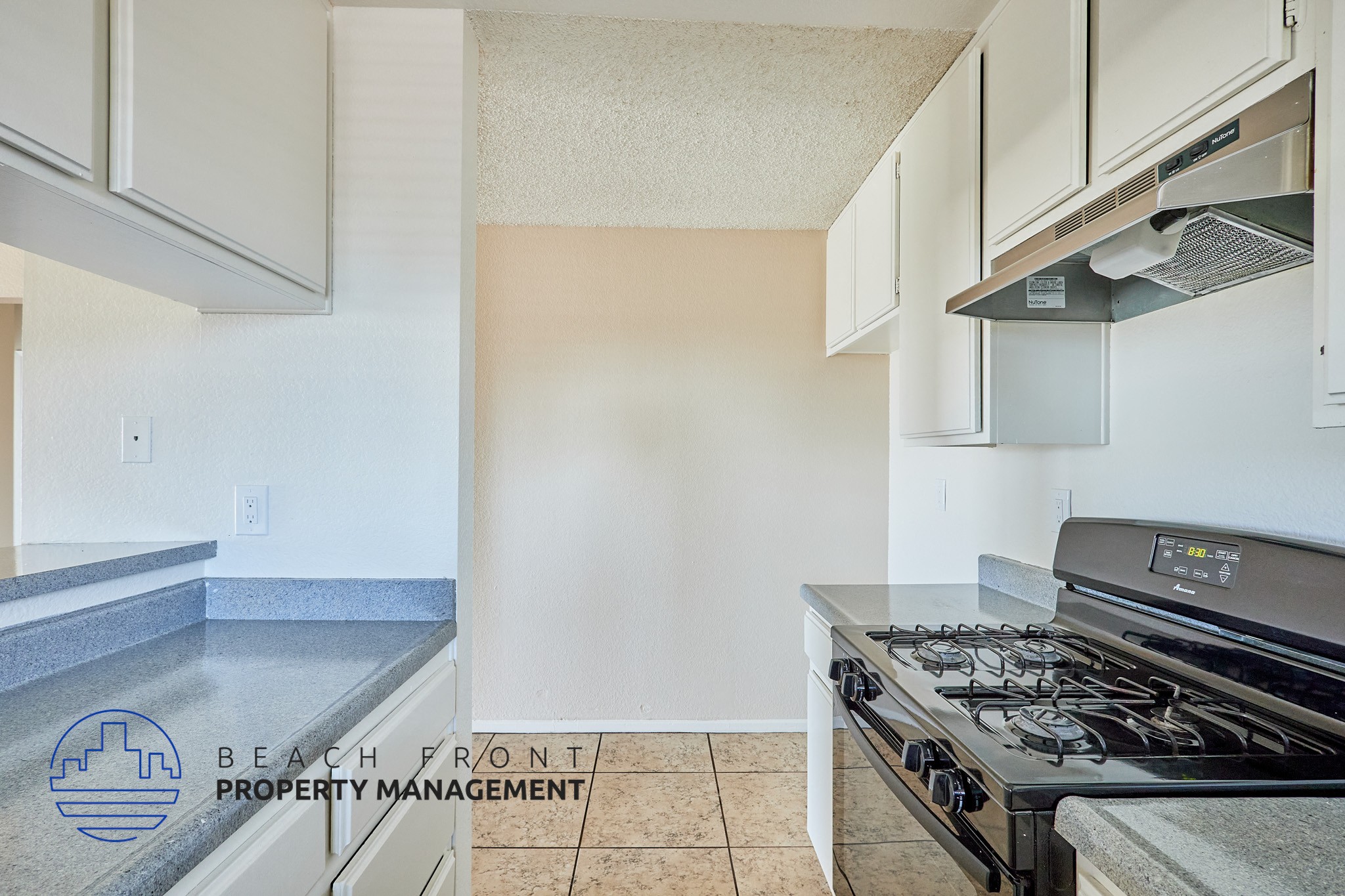A kitchen with a stove top oven and a logo for Beach Front Property Management.