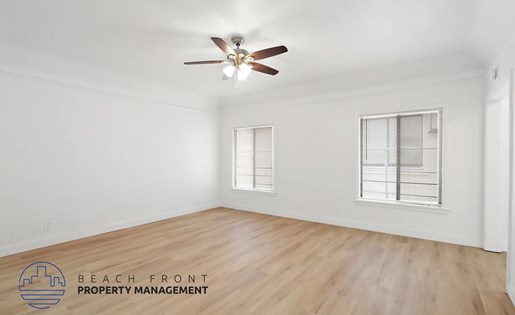 A room with a ceiling fan and two windows.