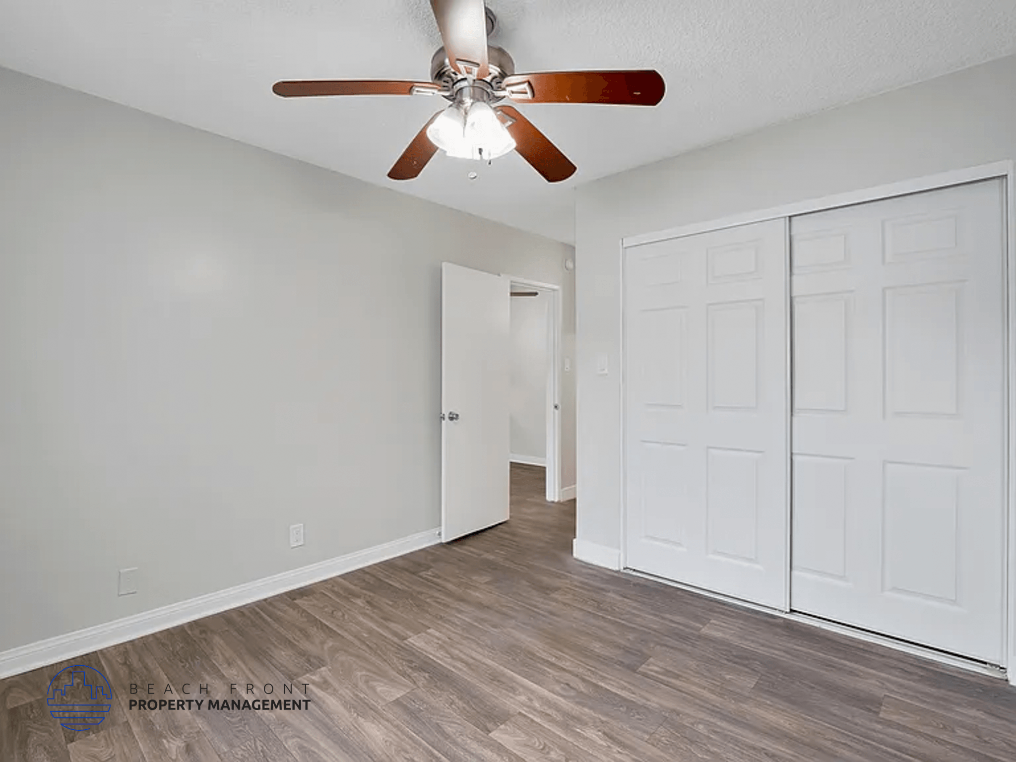 A room with a ceiling fan and a white door.