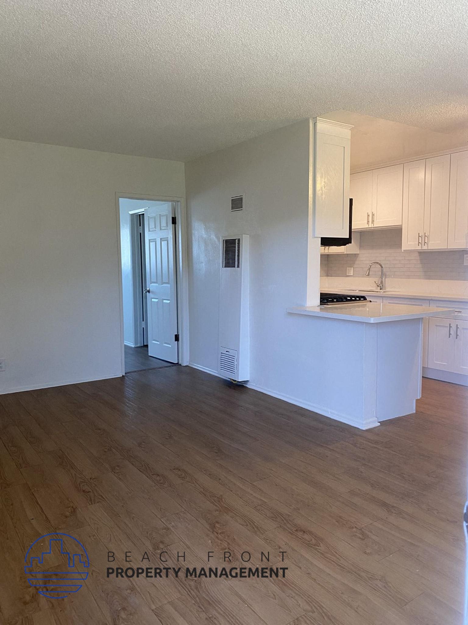 an empty kitchen with white cabinets and a wood floor