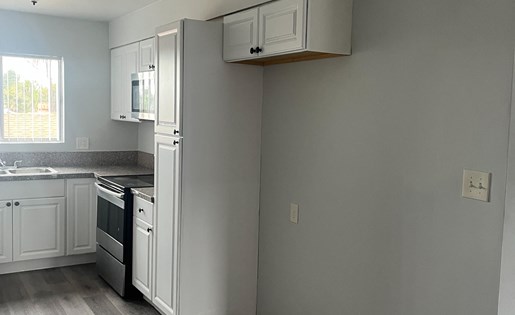 A kitchen with white cabinets and a black stove top oven.