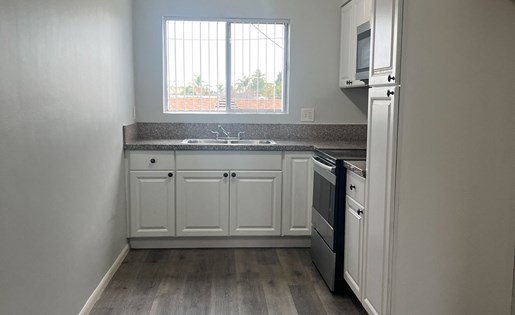 A kitchen with white cabinets and a wooden floor.