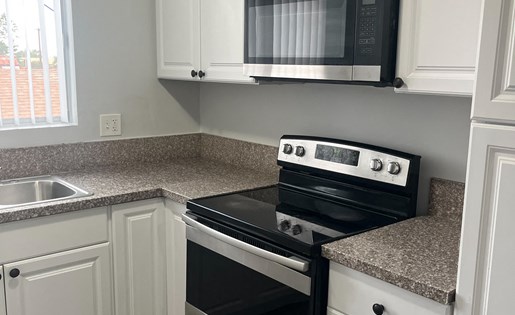 A kitchen with a black stove top oven and white cabinets.