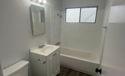 A white bathroom with a toilet, sink, and mirror.