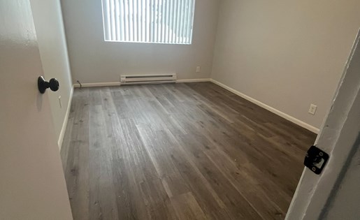 A room with a ceiling fan and wooden flooring.