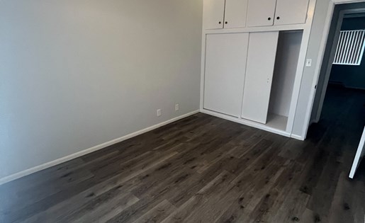 A room with a ceiling fan and wooden flooring.