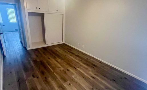 A room with a ceiling fan and wooden flooring.