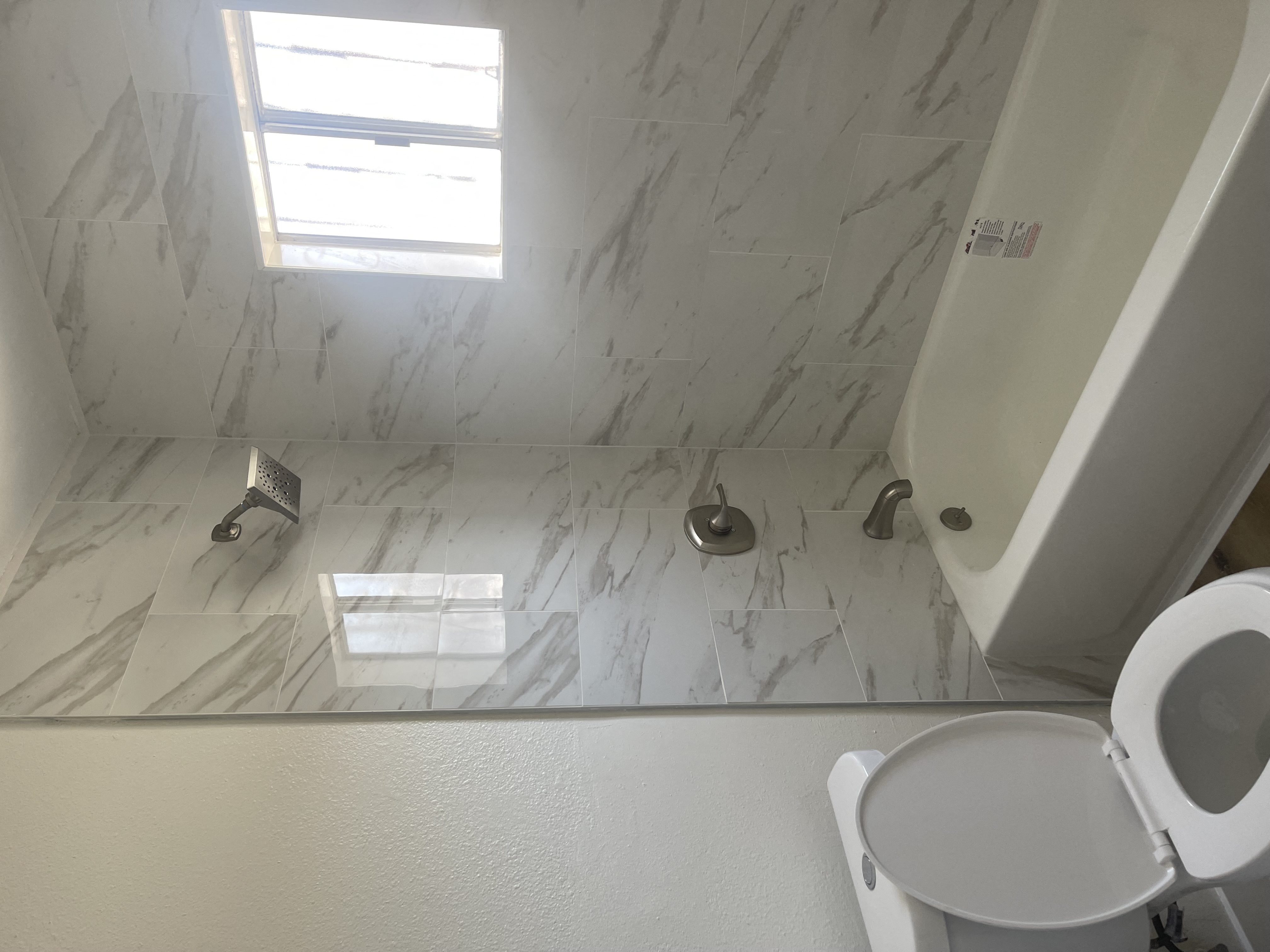 a white bathroom with a toilet and a tub and a window