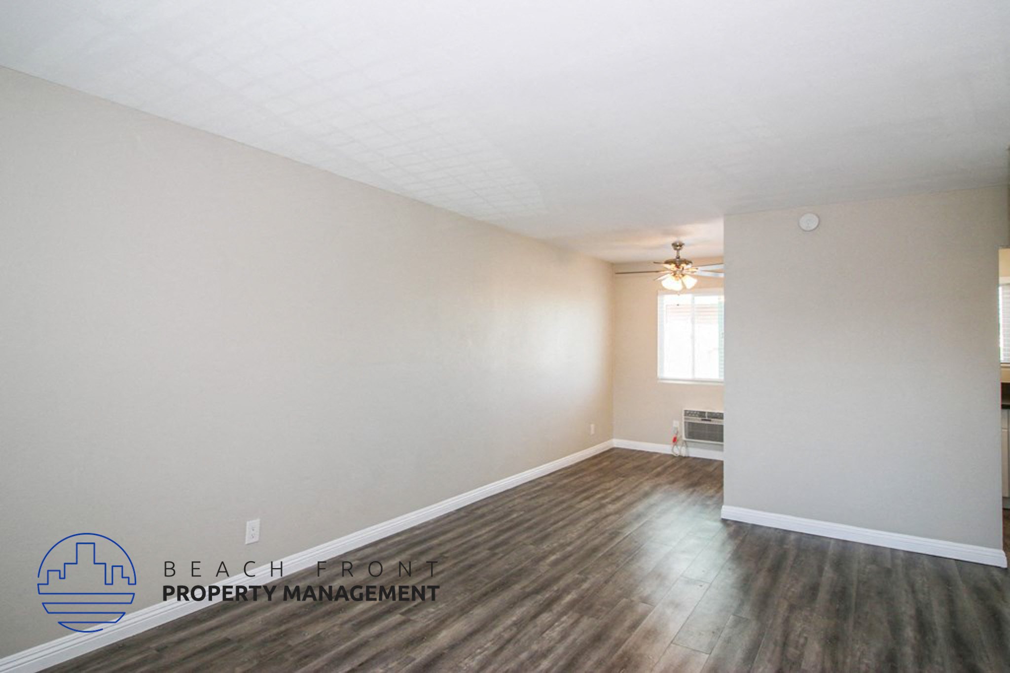the spacious living room with hard wood flooring and white walls