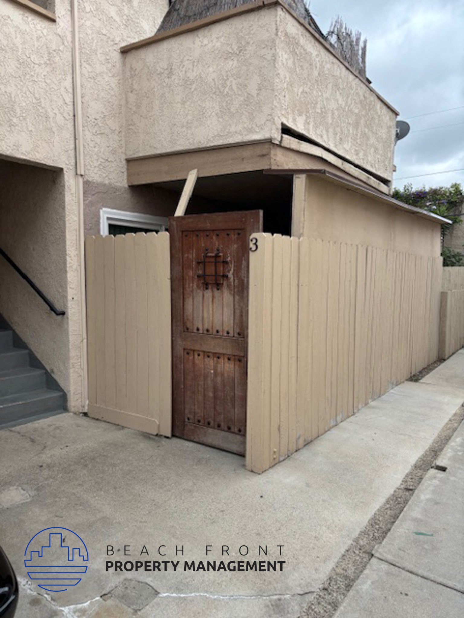 A wooden door is on a building with a sign that says Beach Front Property Management.