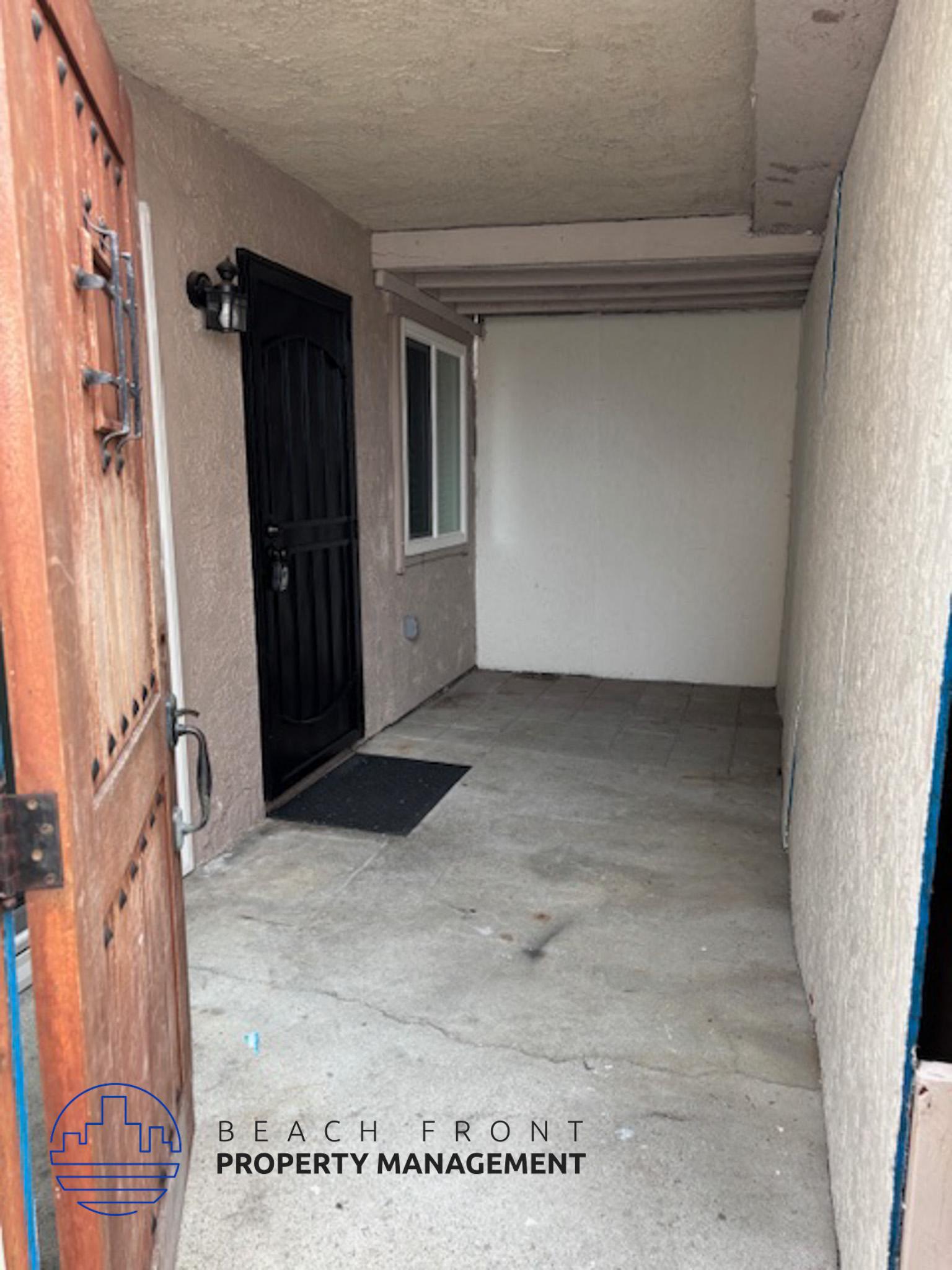 A door with a handle and a window is on the left side of a room with a mat on the floor.