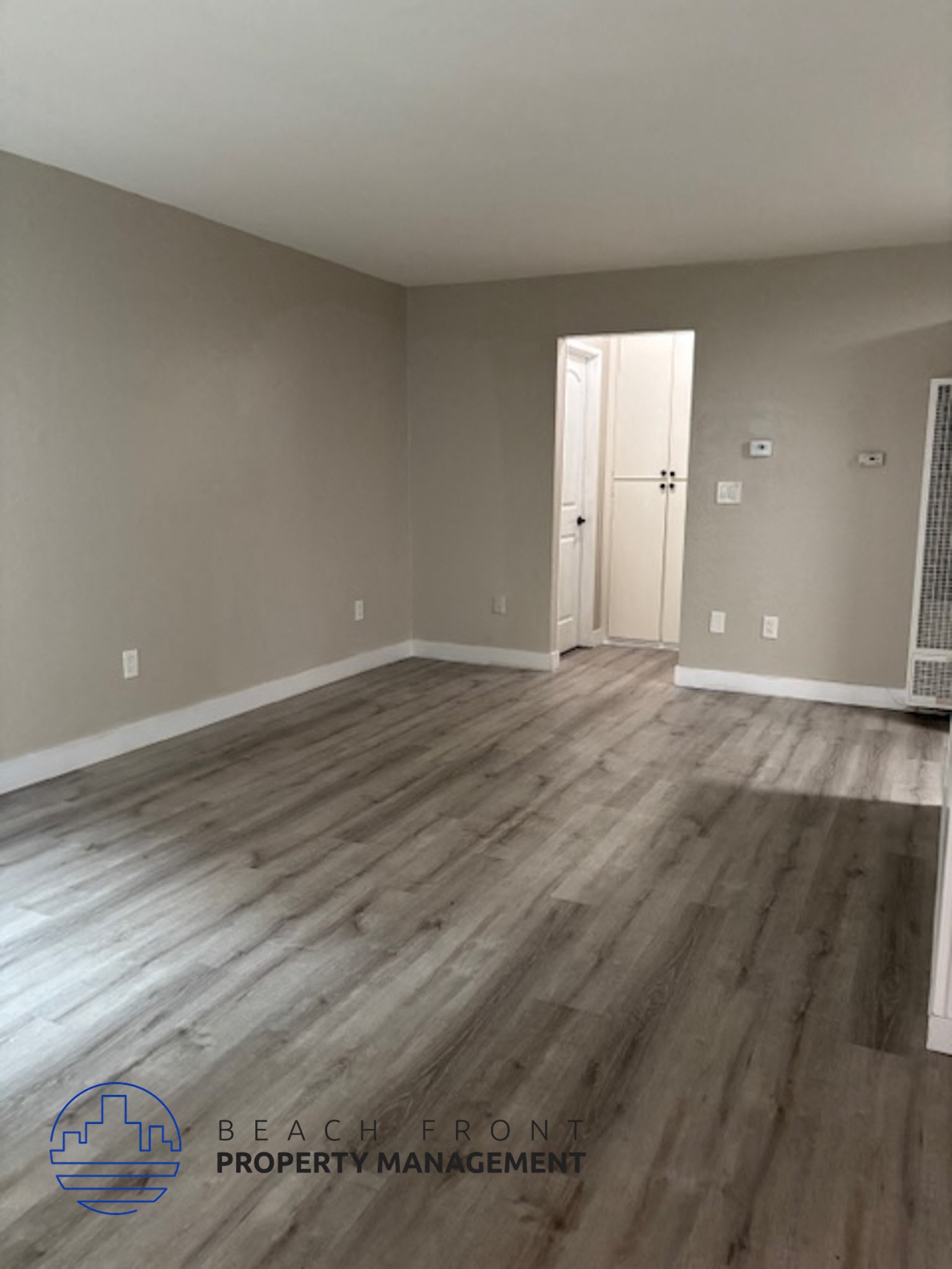 A room with wooden flooring and a doorway leading to another room.