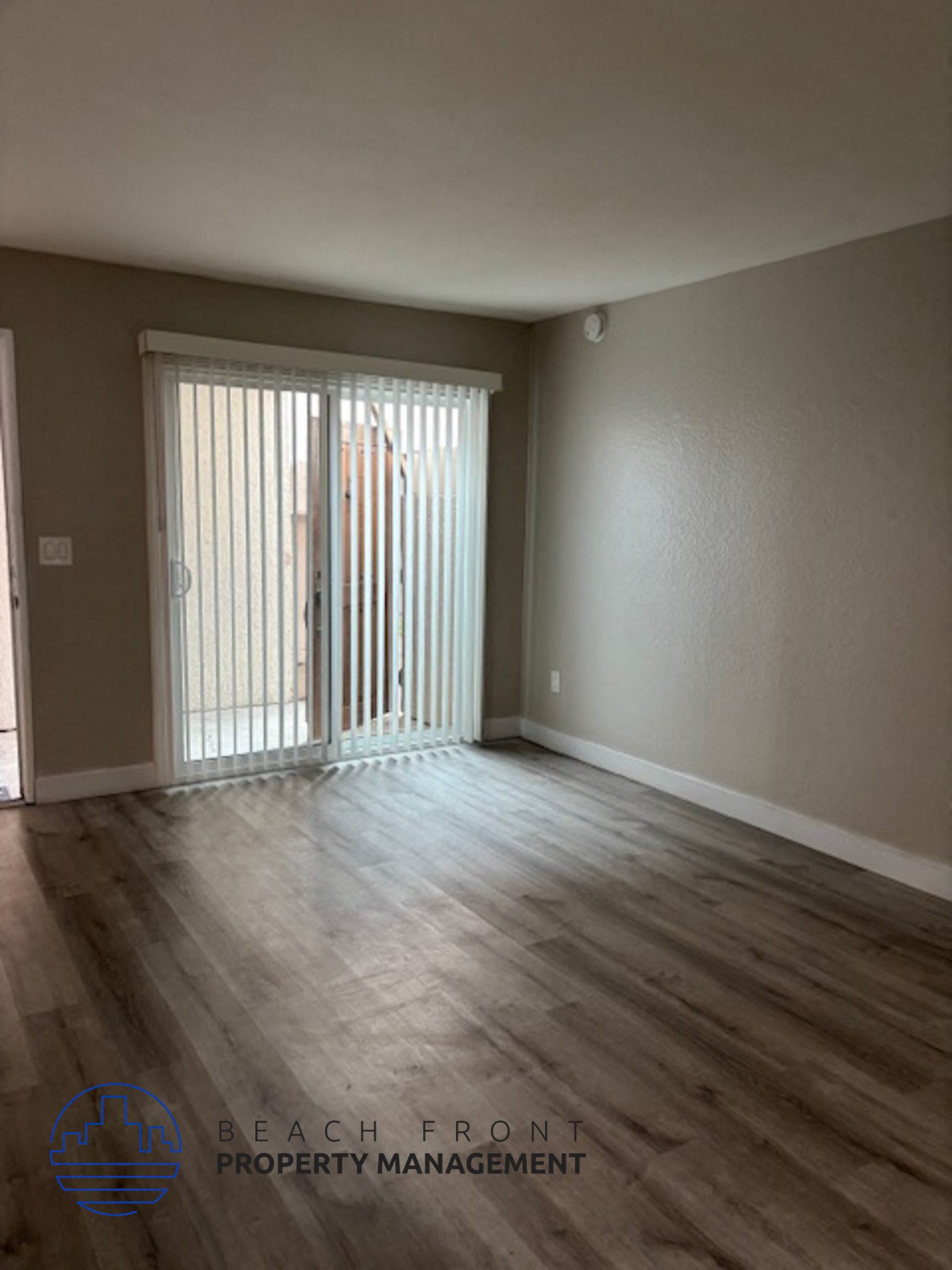 A room with wooden flooring and a sliding glass door.