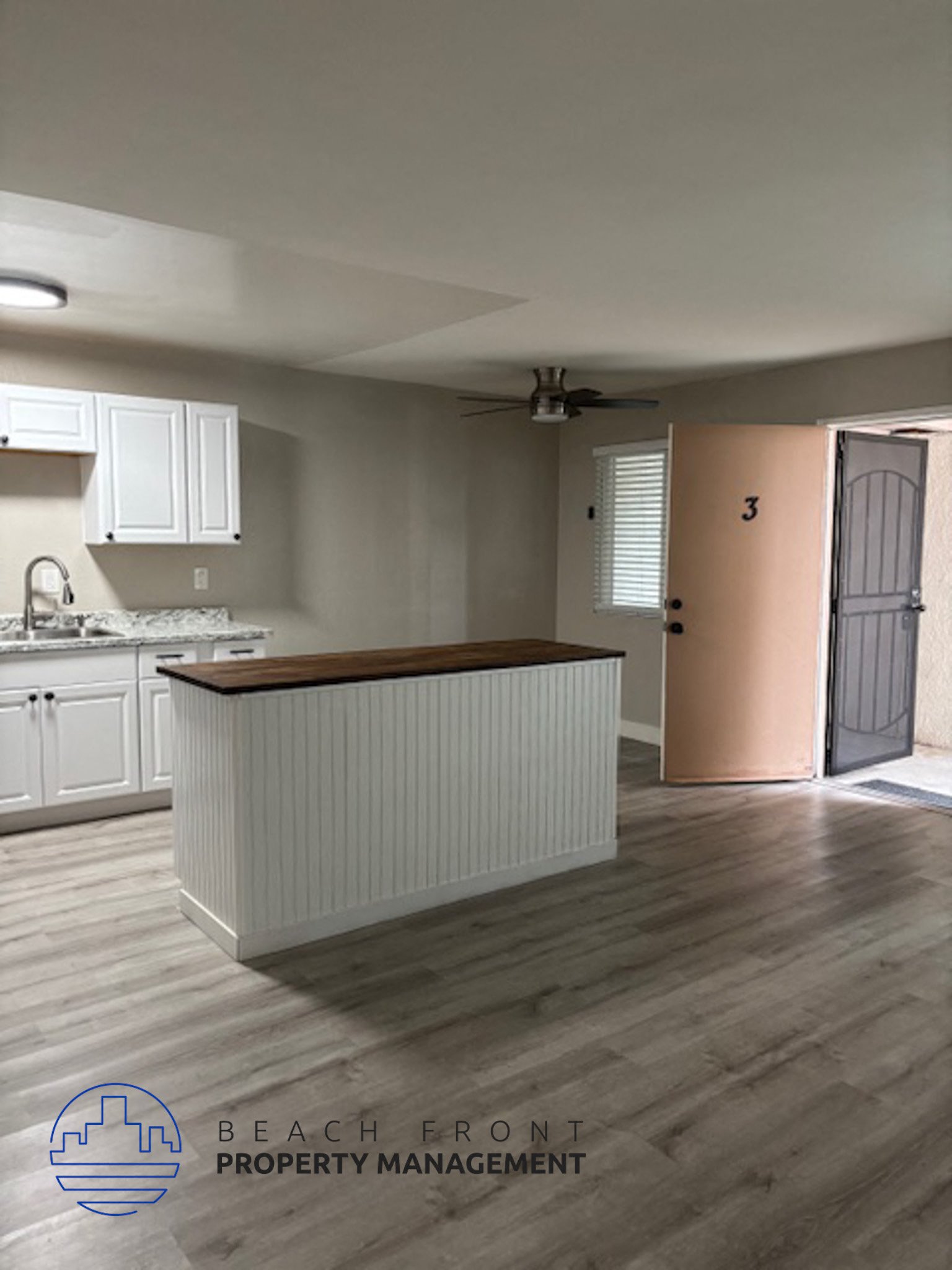 A kitchen with a counter and cabinets with a logo for Beach Front Property Management.