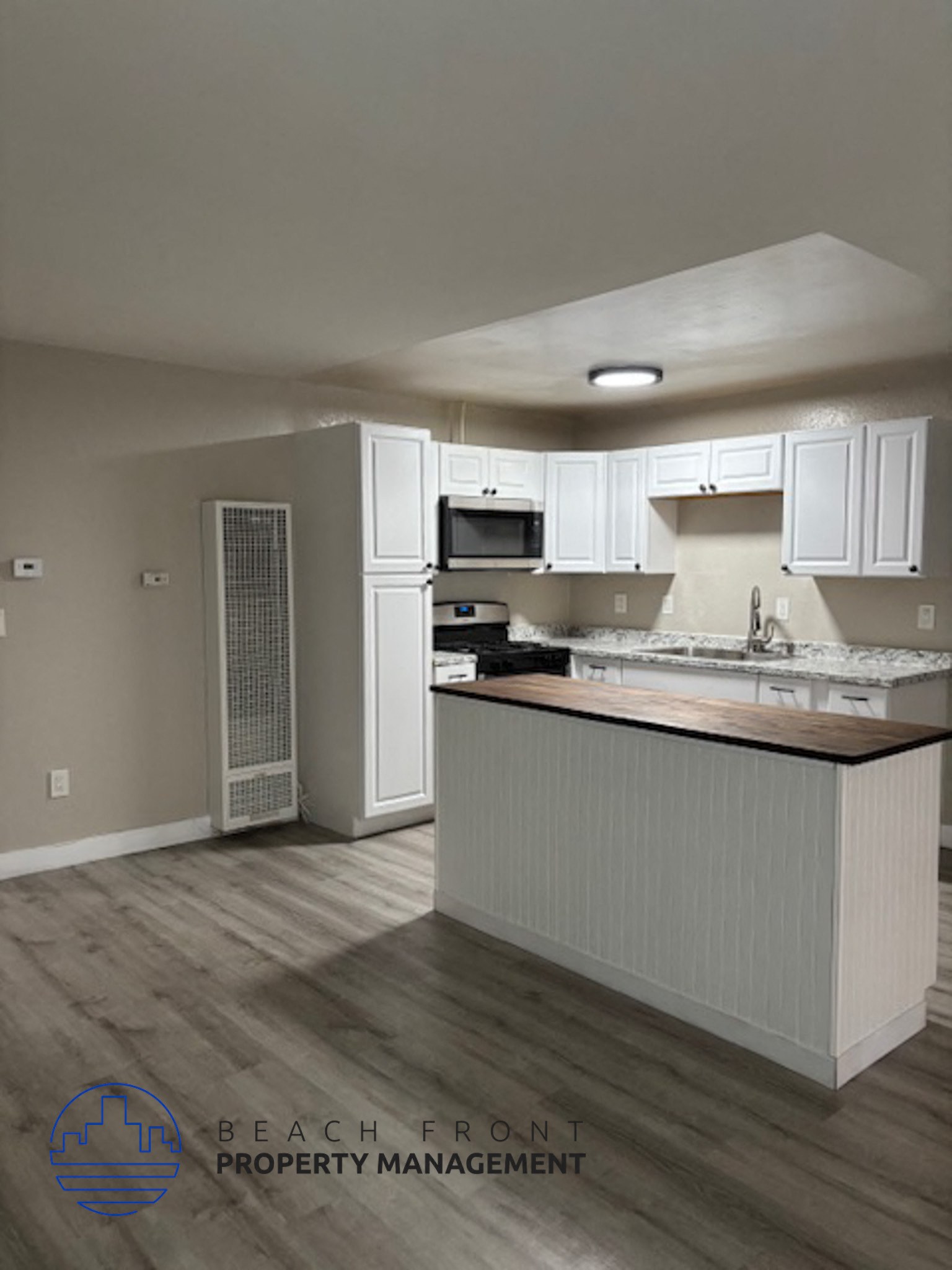 A kitchen with white cabinets and a wooden island.