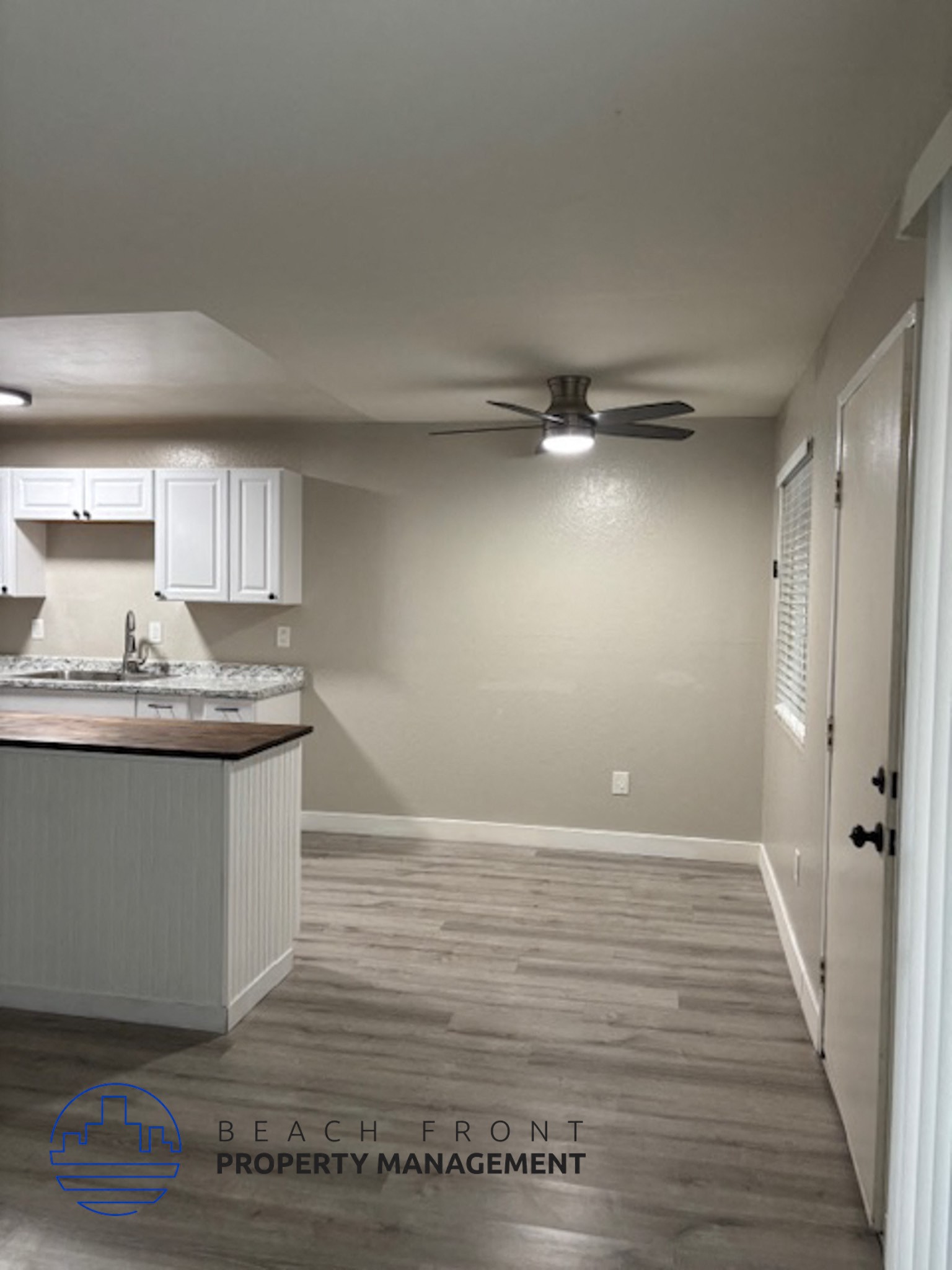 A kitchen with a fan on the ceiling and wooden flooring.