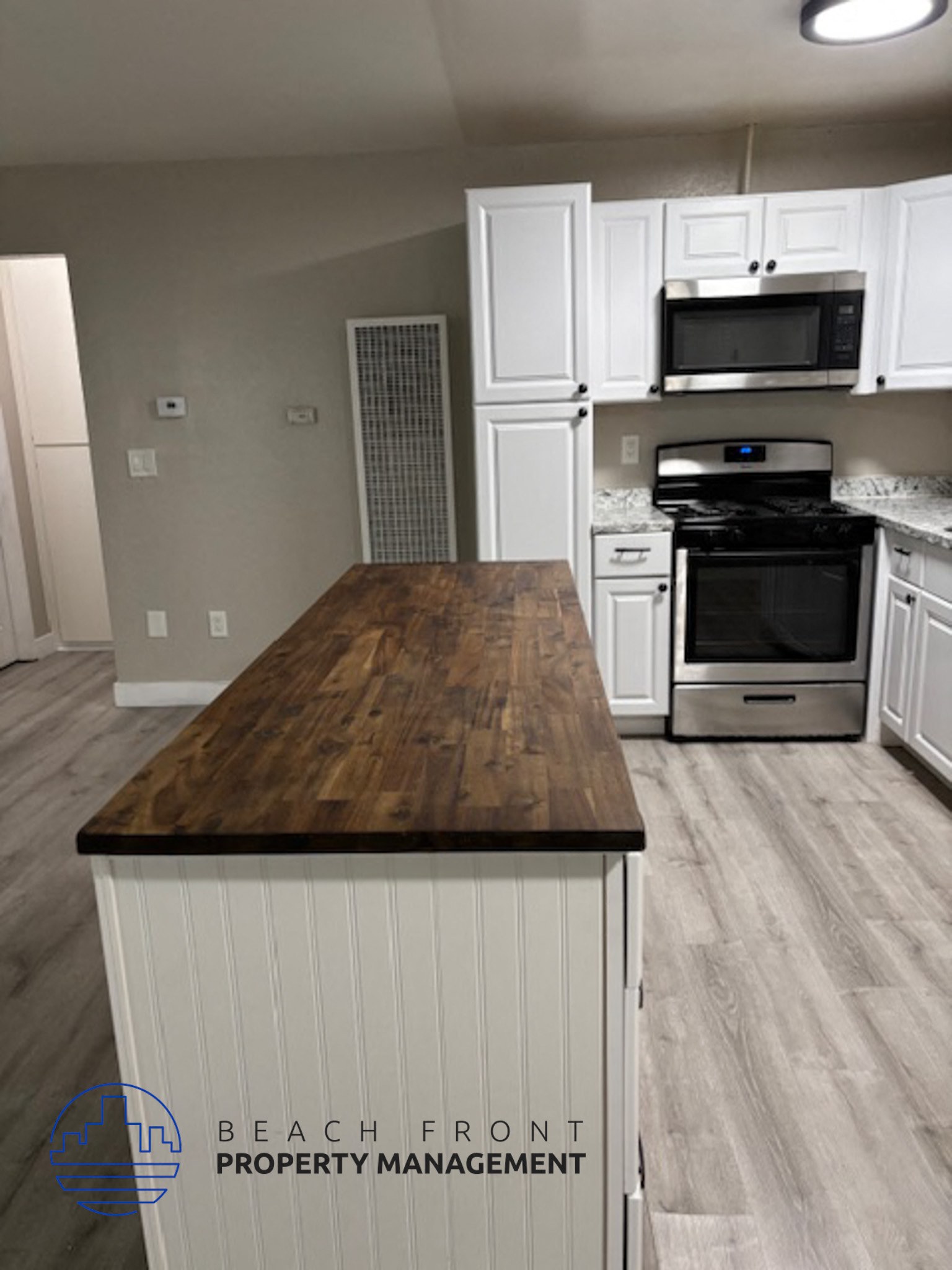 A kitchen with a wooden counter top and white cabinets.