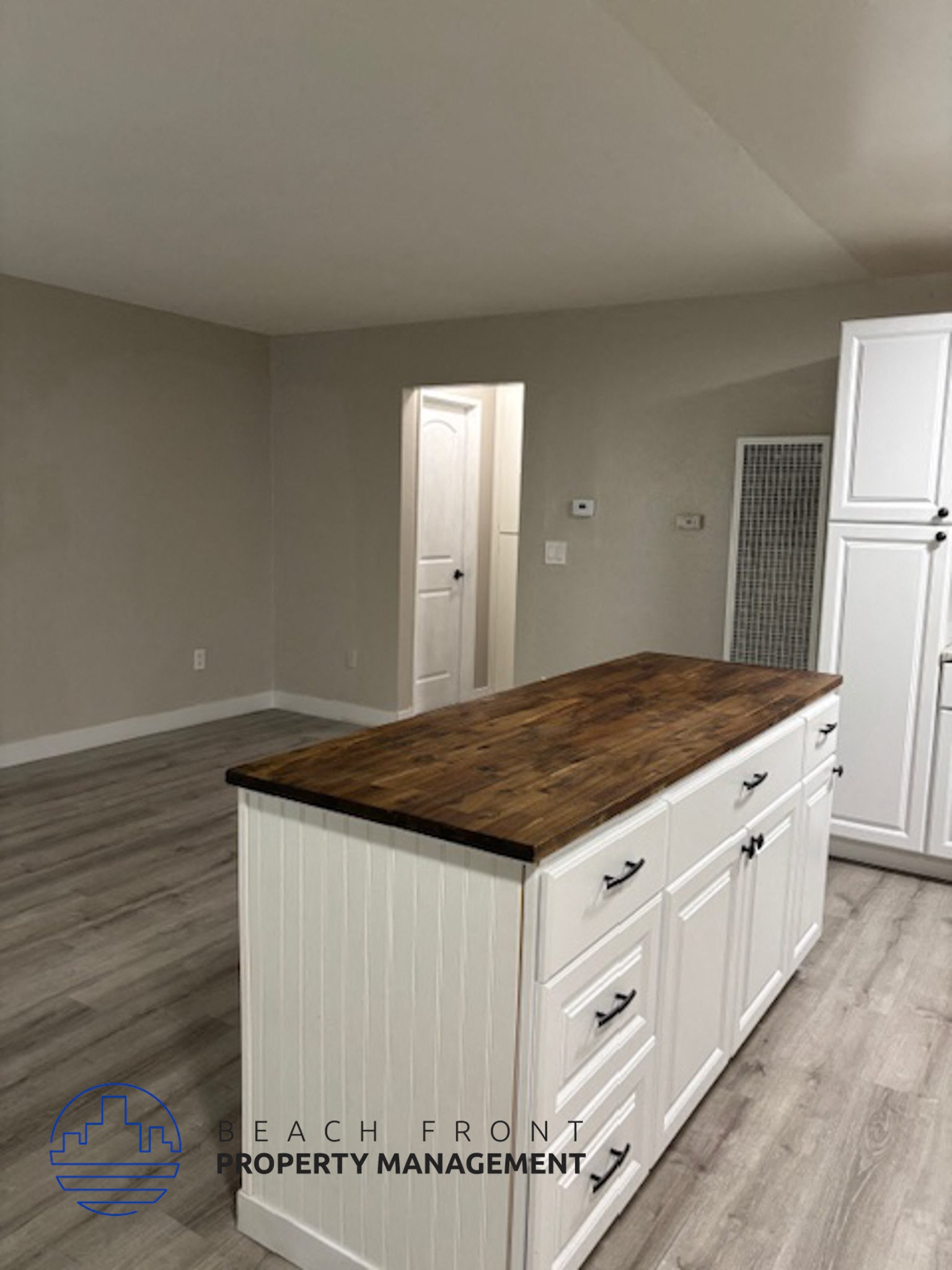 A kitchen island with a wooden top and white cabinets.