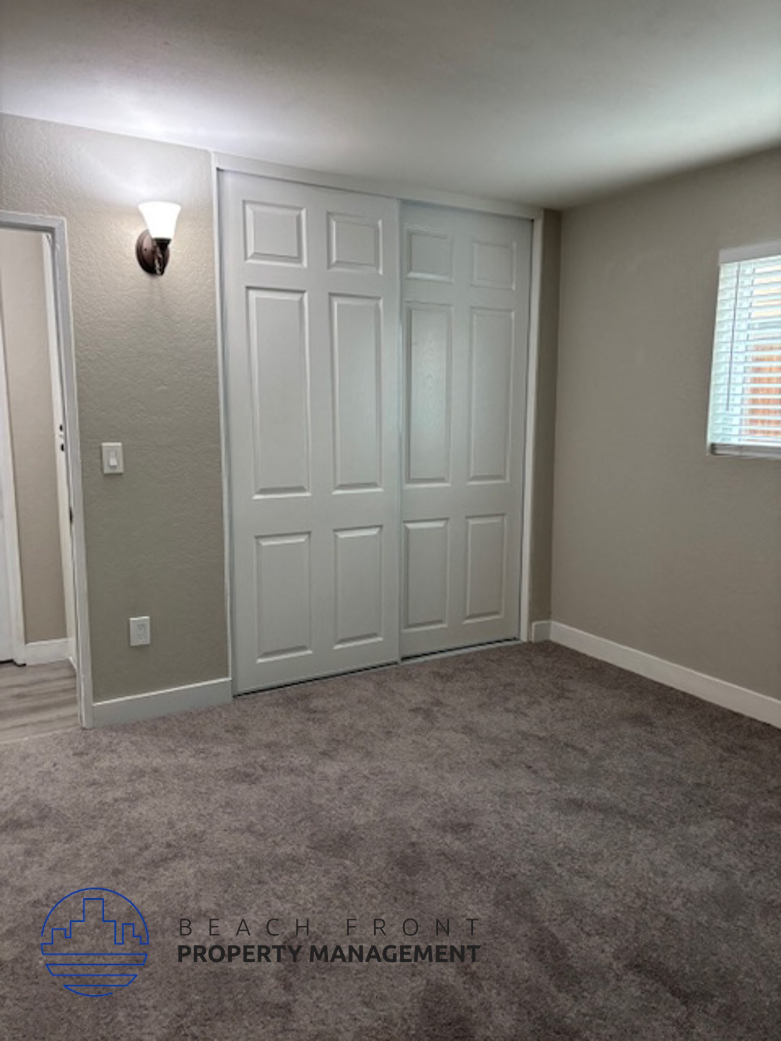 A room with a white door and a light switch on the wall.