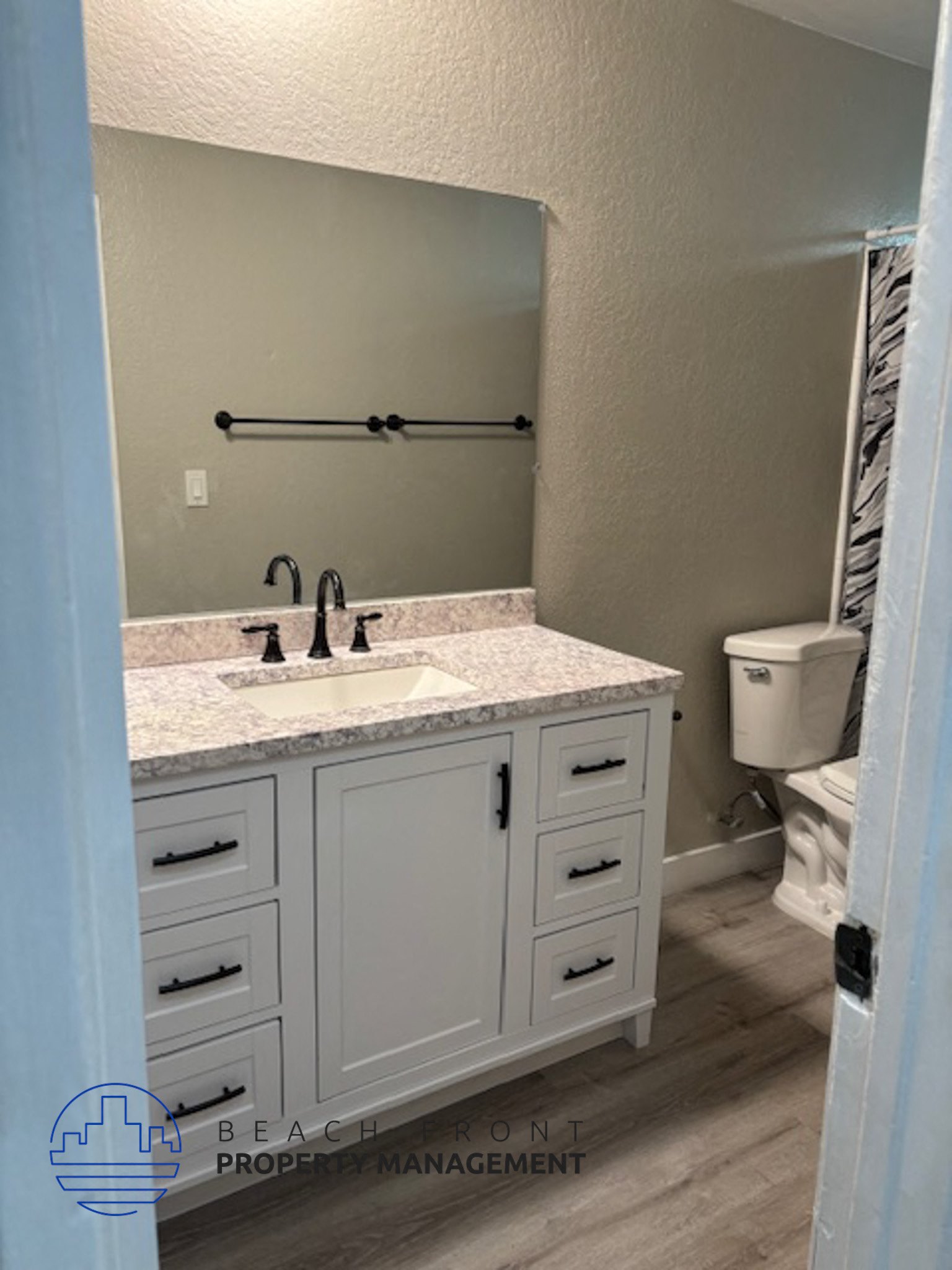 A bathroom with a sink, toilet, and cabinets.