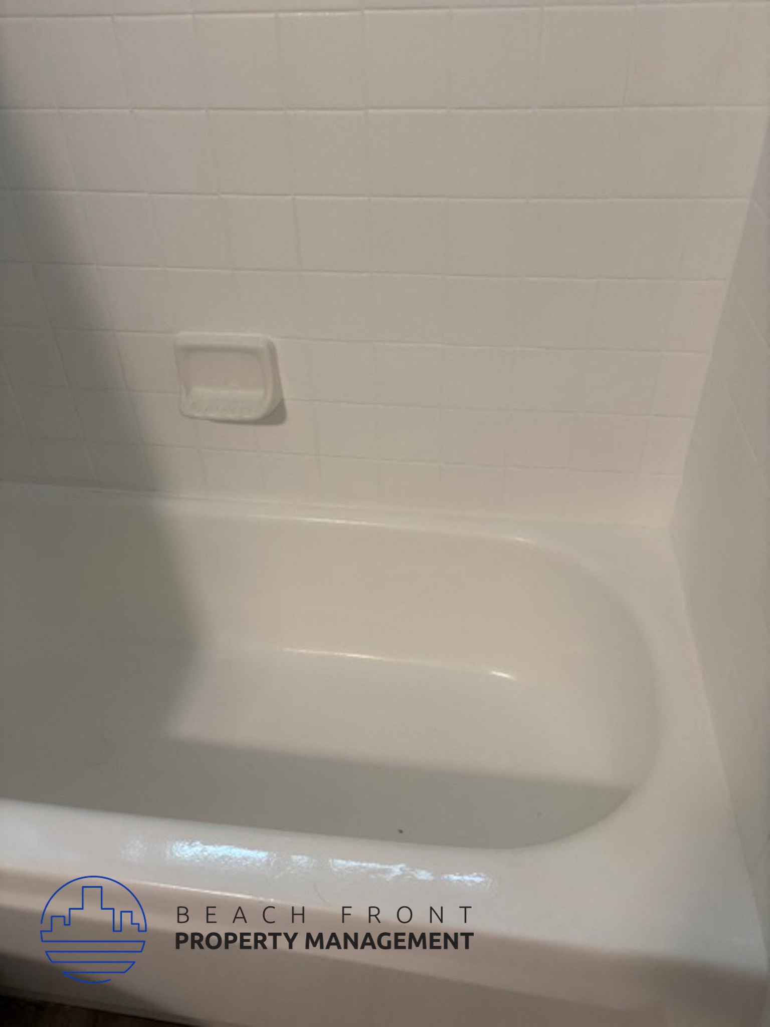 A white bathtub with a logo for Beach Front Property Management.