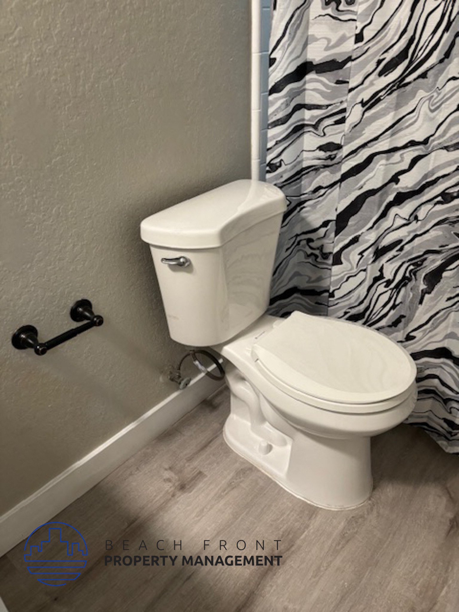 A white toilet with a white tank and a black flush handle in a bathroom.